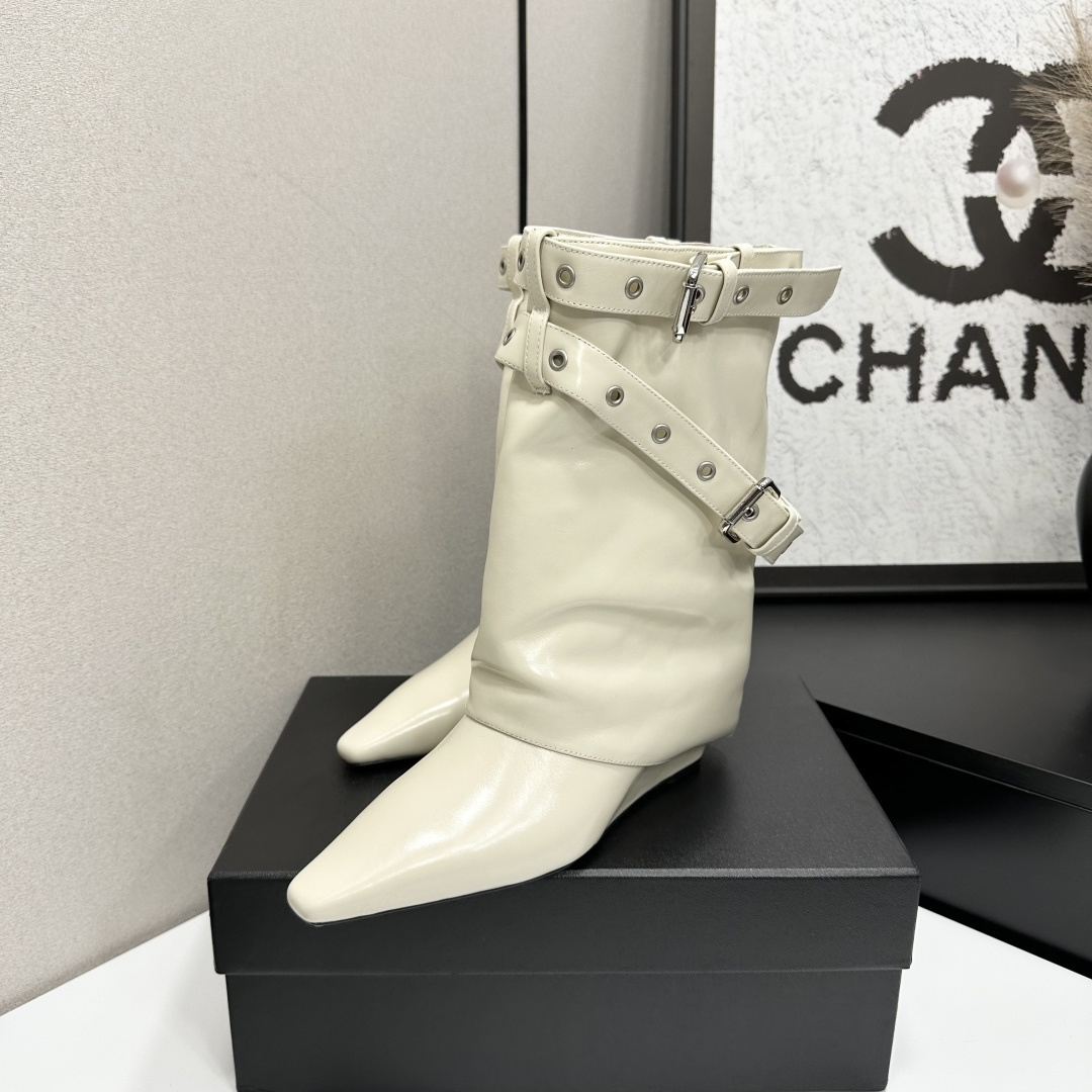 A pair of cream-colored slouchy leather wedge boots with pointed toes and double buckle strap details on a black display box. - Hình 2