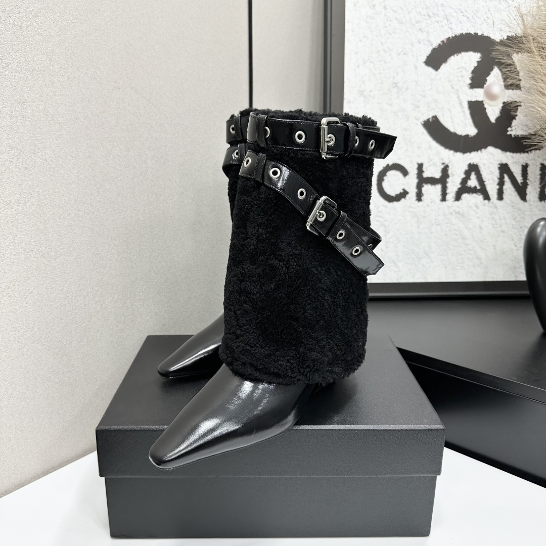 Luxury black shearling ankle boots with silver buckle straps and pointed toes sitting on a black designer box. - Hình 2