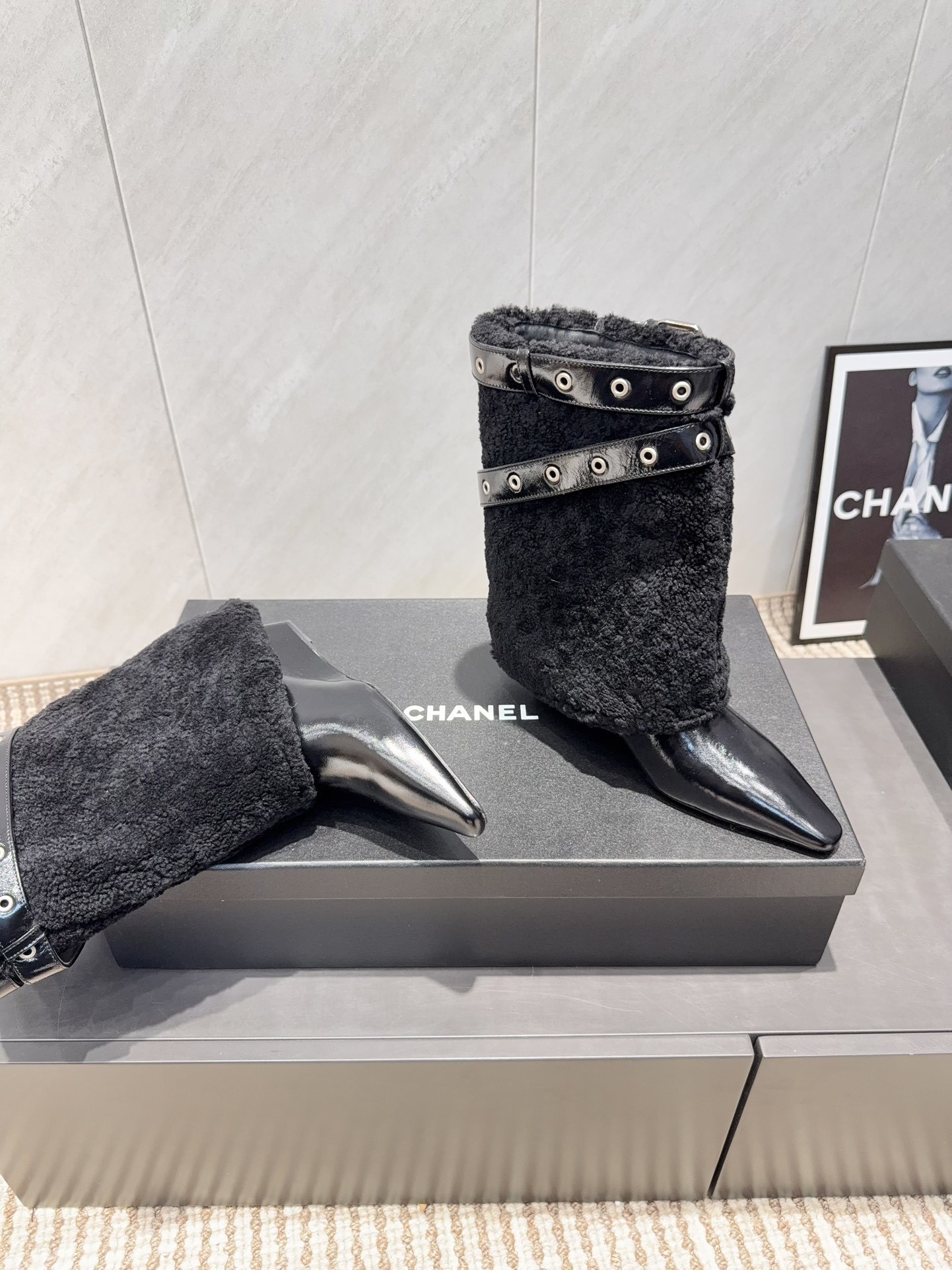 A pair of Chanel black patent leather and shearling ankle boots with silver eyelet buckles and pointed toes on a black box. - Hình 9