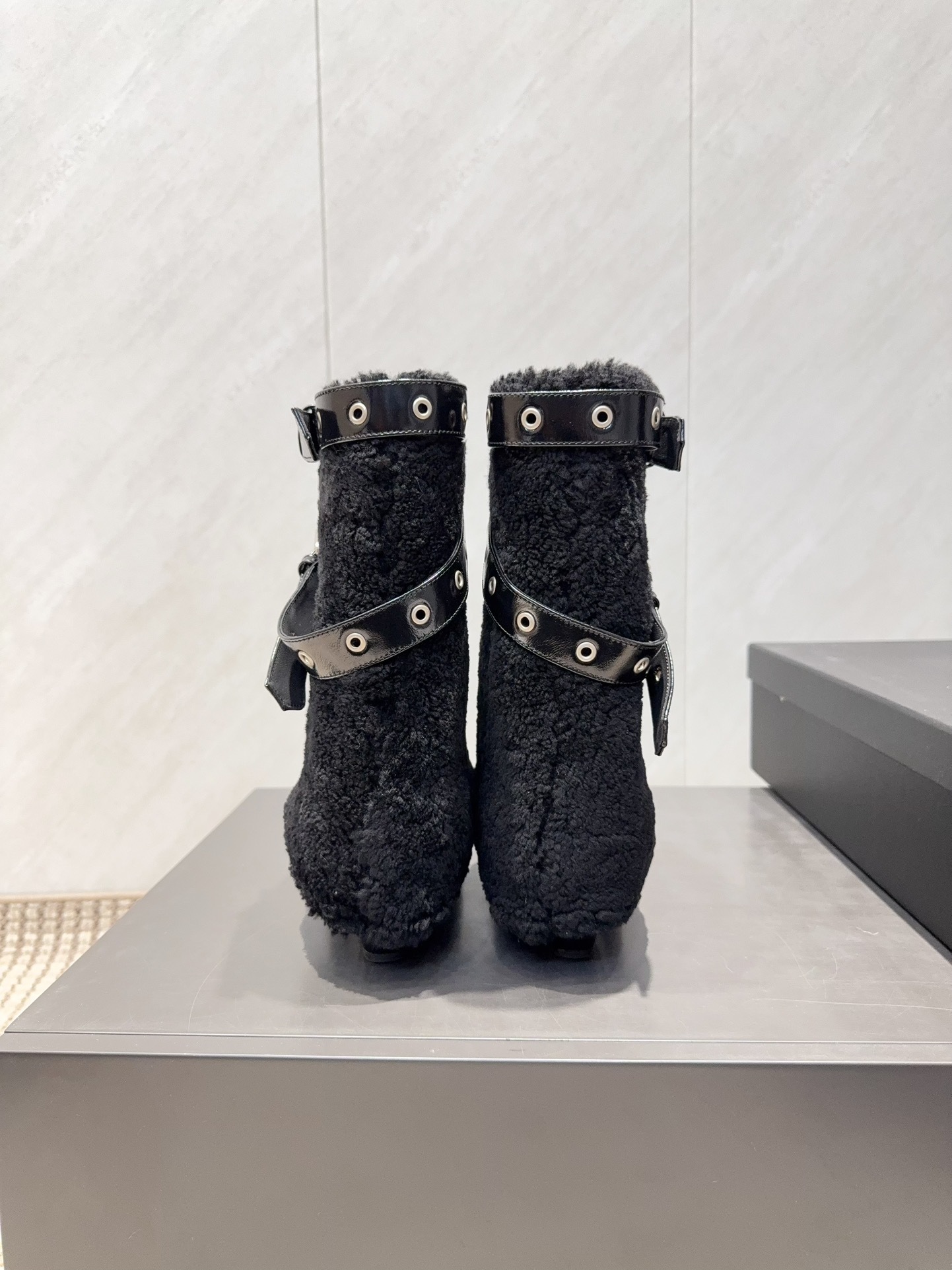 A pair of Chanel black patent leather and shearling ankle boots with silver eyelet buckles and pointed toes on a black box. - Hình 8
