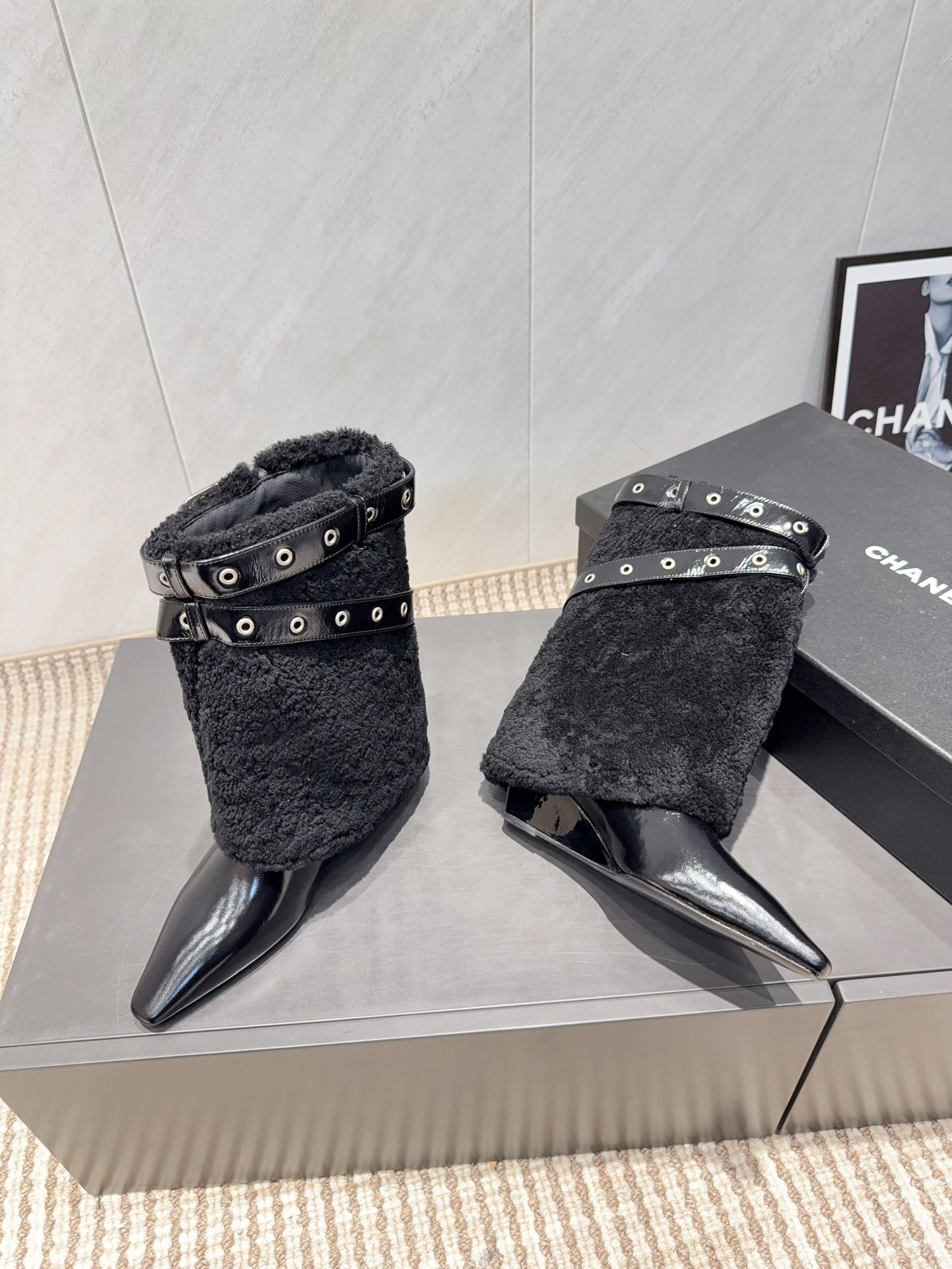 A pair of Chanel black patent leather and shearling ankle boots with silver eyelet buckles and pointed toes on a black box. - Hình 3