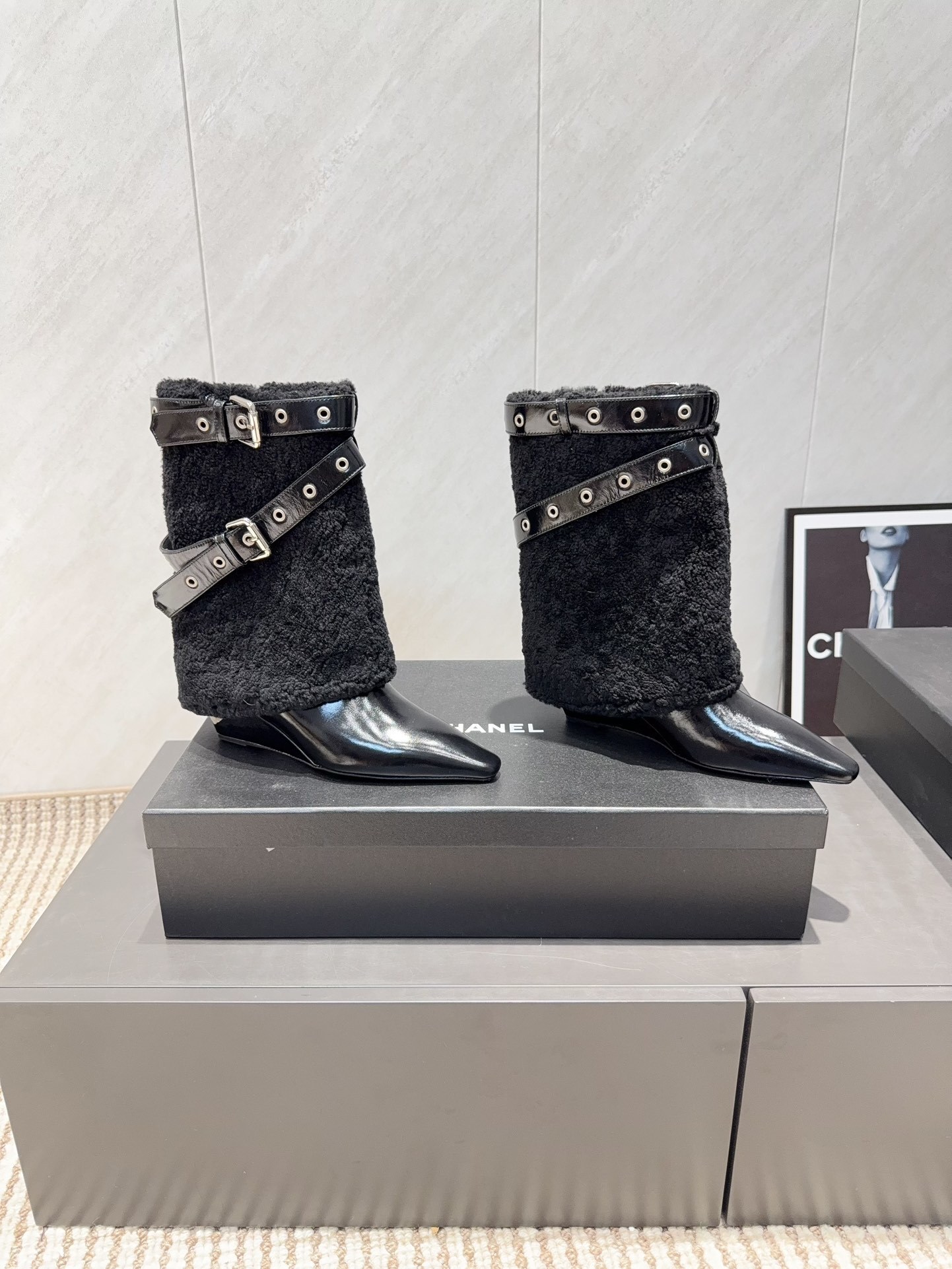A pair of Chanel black patent leather and shearling ankle boots with silver eyelet buckles and pointed toes on a black box. - Hình 2
