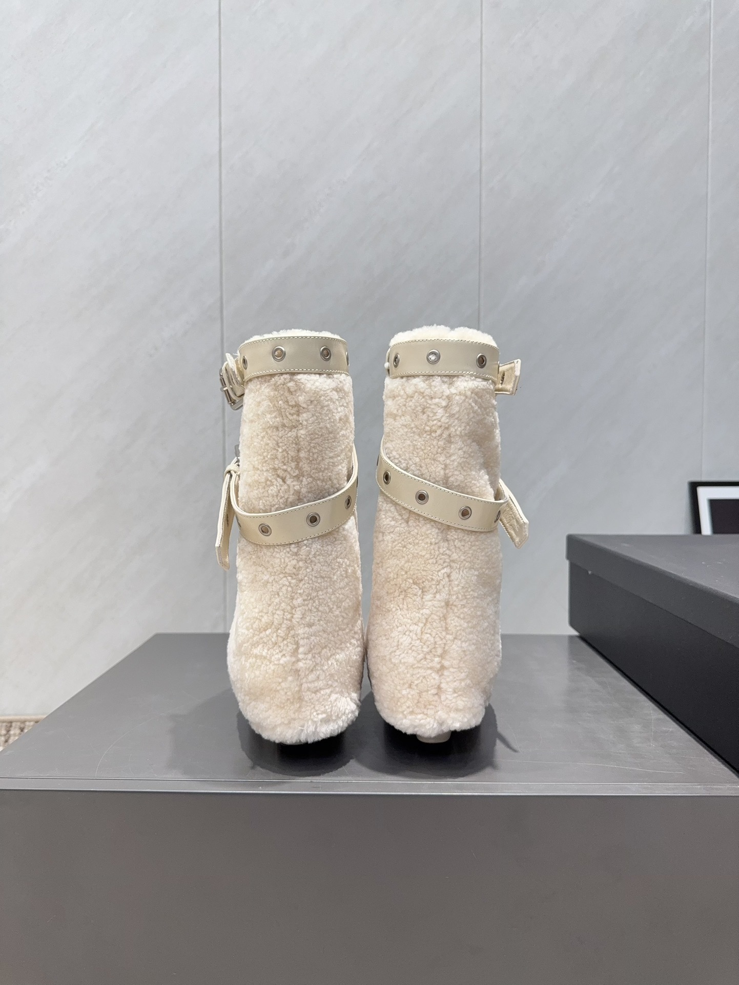 Pair of luxury cream pointed toe ankle boots with plush shearling shafts and decorative buckle straps displayed on a black box. - Hình 8
