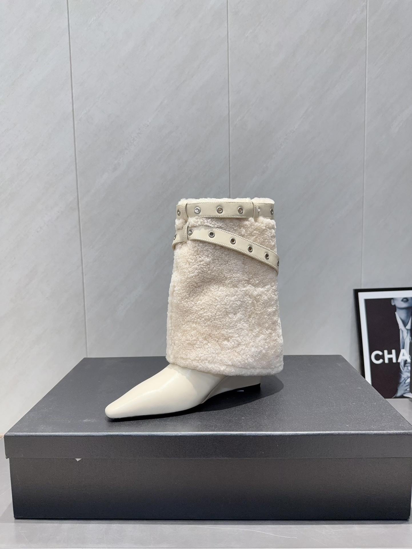 Pair of luxury cream pointed toe ankle boots with plush shearling shafts and decorative buckle straps displayed on a black box. - Hình 6