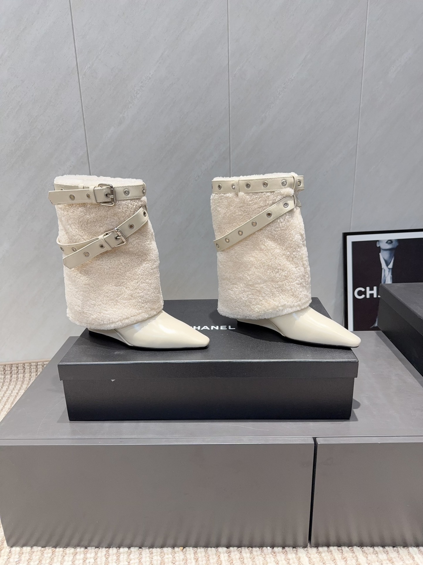 Pair of luxury cream pointed toe ankle boots with plush shearling shafts and decorative buckle straps displayed on a black box. - Hình 2
