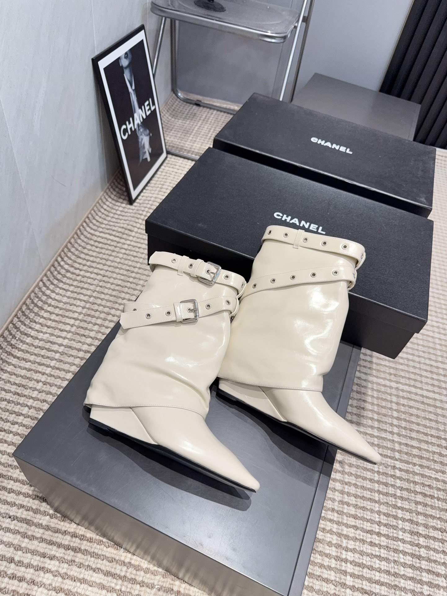 A pair of Chanel cream leather slouchy ankle boots with silver buckle straps and pointed toes placed on a black branded box. - Hình 9