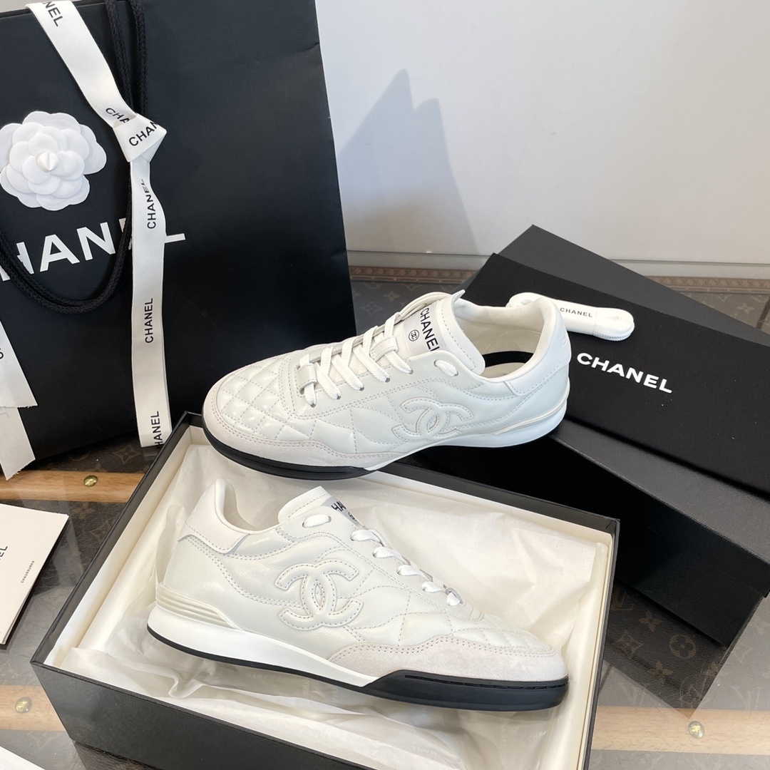 Pair of white Chanel quilted leather sneakers with CC logo, shown with original black packaging and shopping bag. - Hình 8
