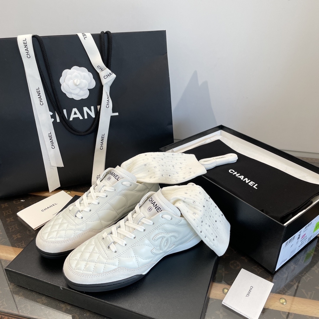 Pair of white Chanel quilted leather sneakers with CC logo, shown with original black packaging and shopping bag. - Hình 5