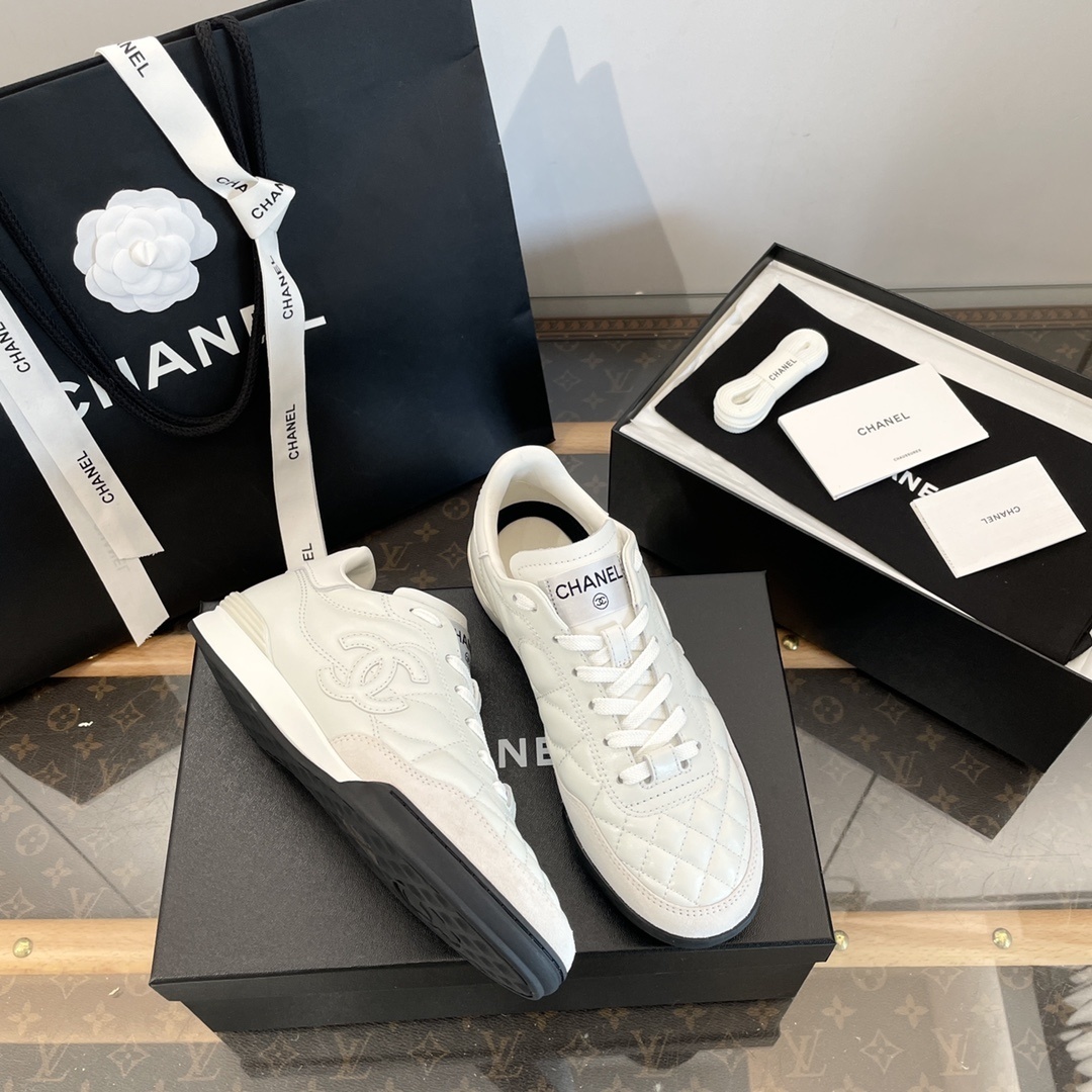 Pair of white Chanel quilted leather sneakers with CC logo, shown with original black packaging and shopping bag. - Hình 4