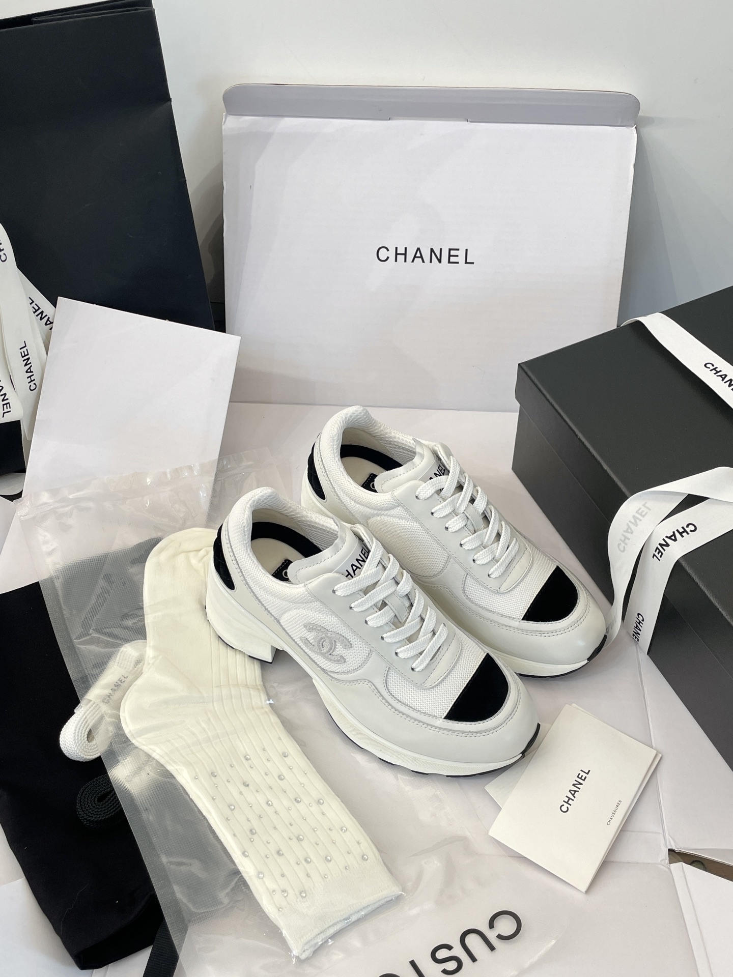 Luxury Chanel white and black mesh leather sneakers with chunky heels on a white box with branded packaging. - Hình 5