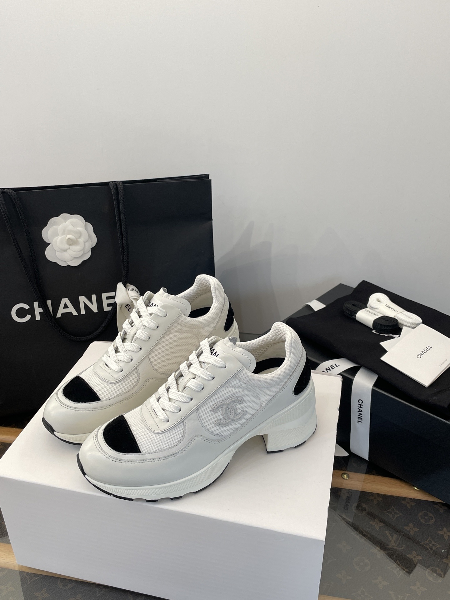 Luxury Chanel white and black mesh leather sneakers with chunky heels on a white box with branded packaging. - Hình 3