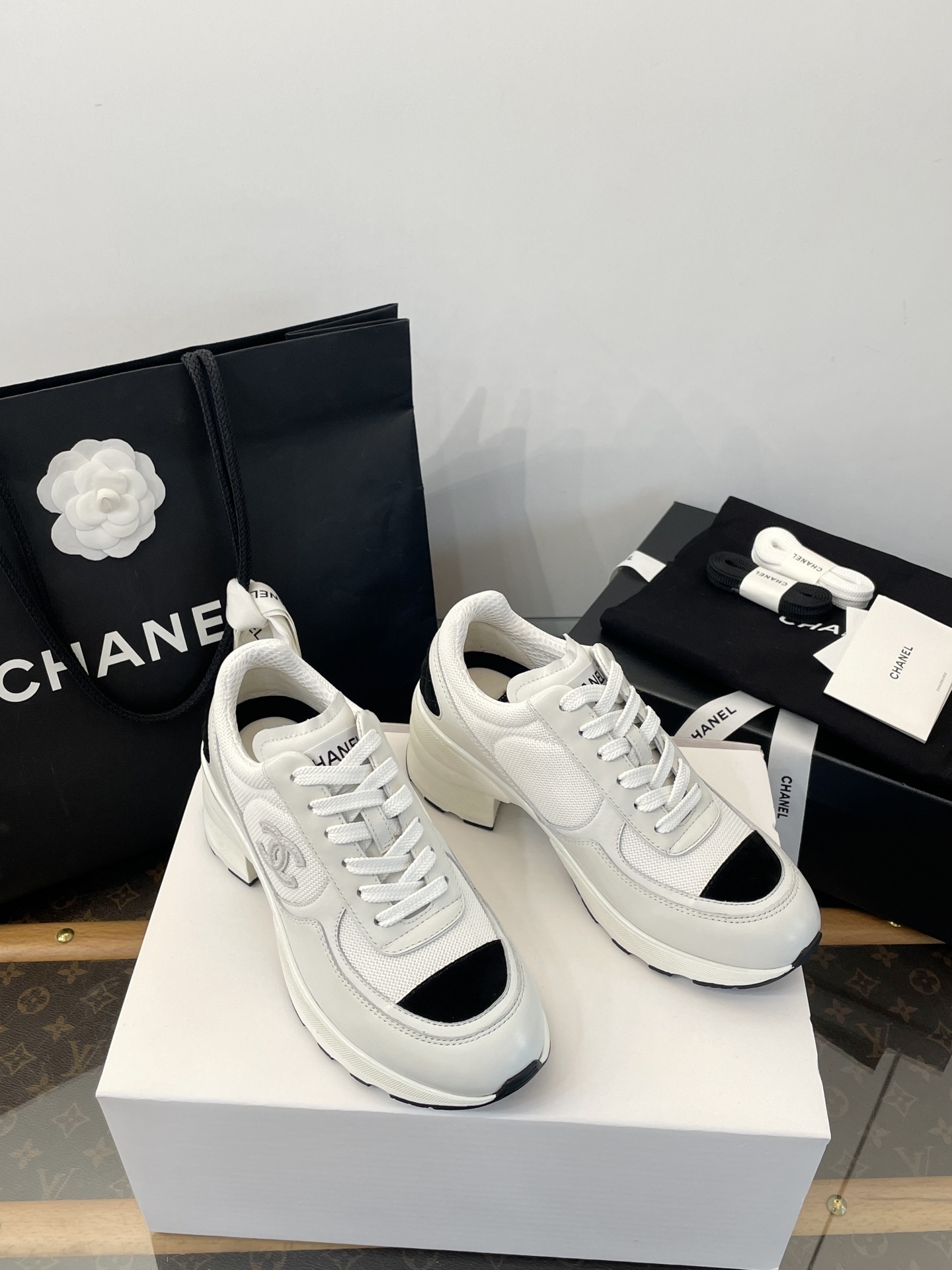 Luxury Chanel white and black mesh leather sneakers with chunky heels on a white box with branded packaging. - Hình 2