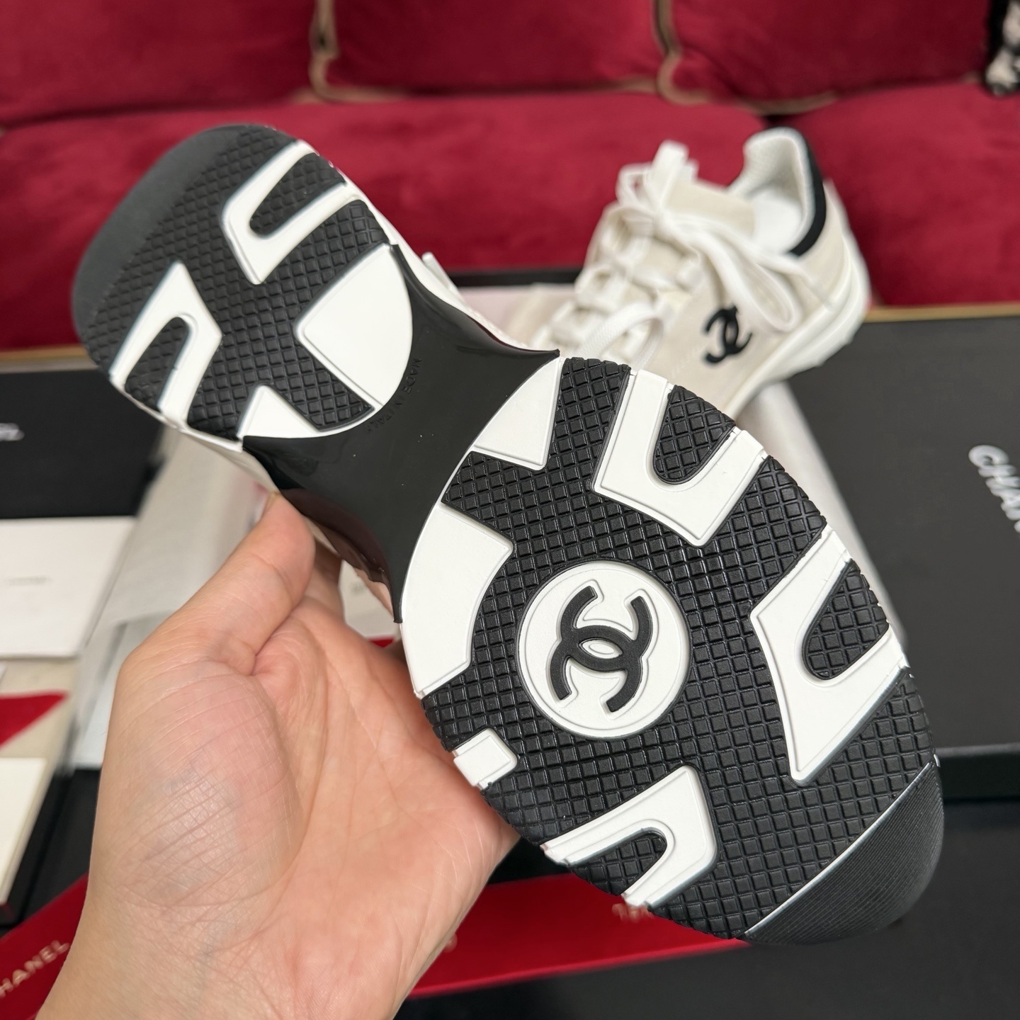 Authentic Chanel sneakers in cream and black featuring the iconic CC logo, presented in a luxury box with red ribbons. - Hình 9