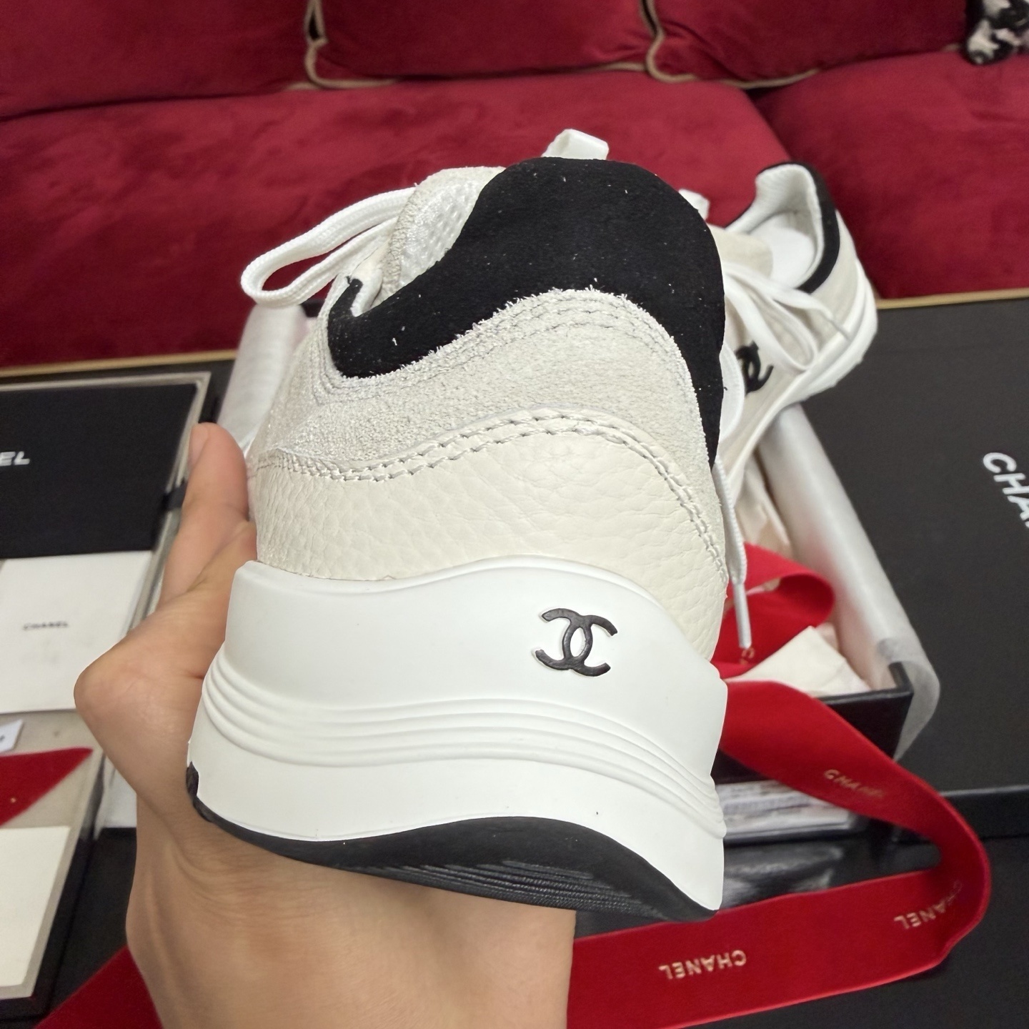 Authentic Chanel sneakers in cream and black featuring the iconic CC logo, presented in a luxury box with red ribbons. - Hình 8