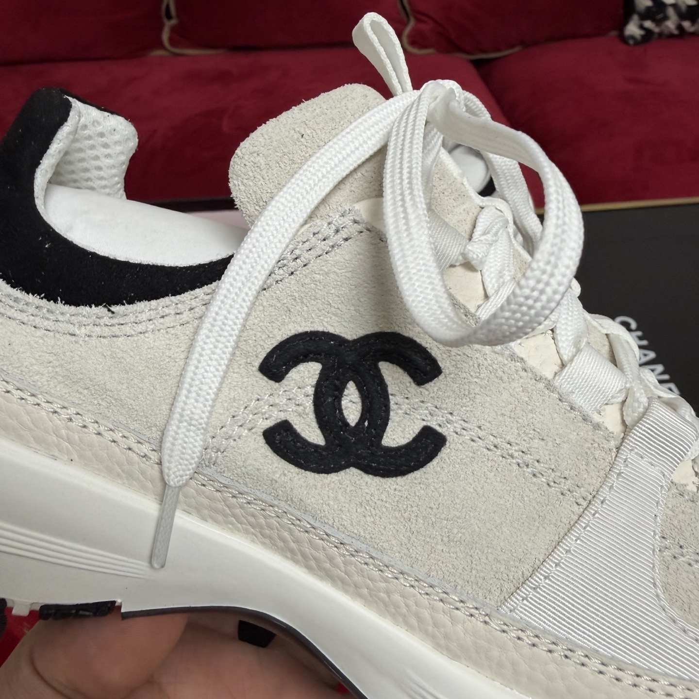 Authentic Chanel sneakers in cream and black featuring the iconic CC logo, presented in a luxury box with red ribbons. - Hình 7