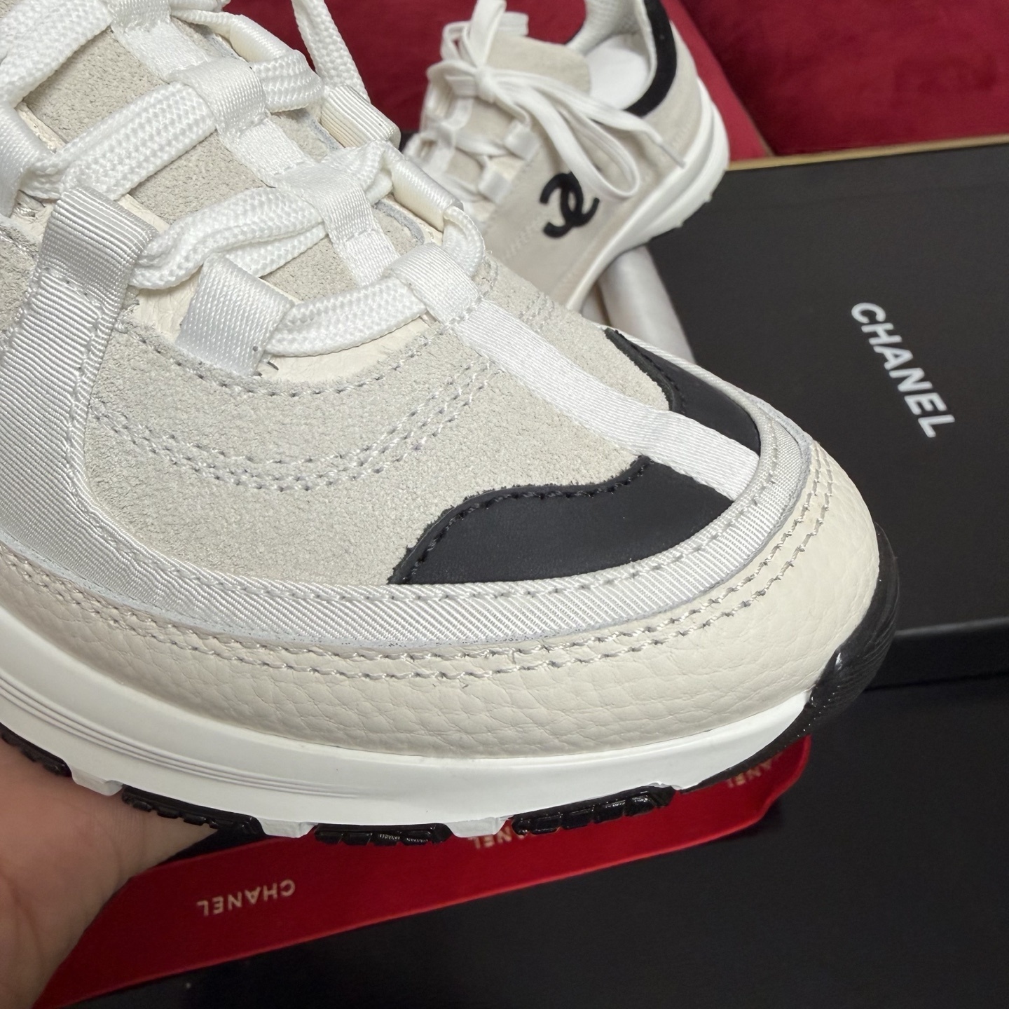 Authentic Chanel sneakers in cream and black featuring the iconic CC logo, presented in a luxury box with red ribbons. - Hình 6