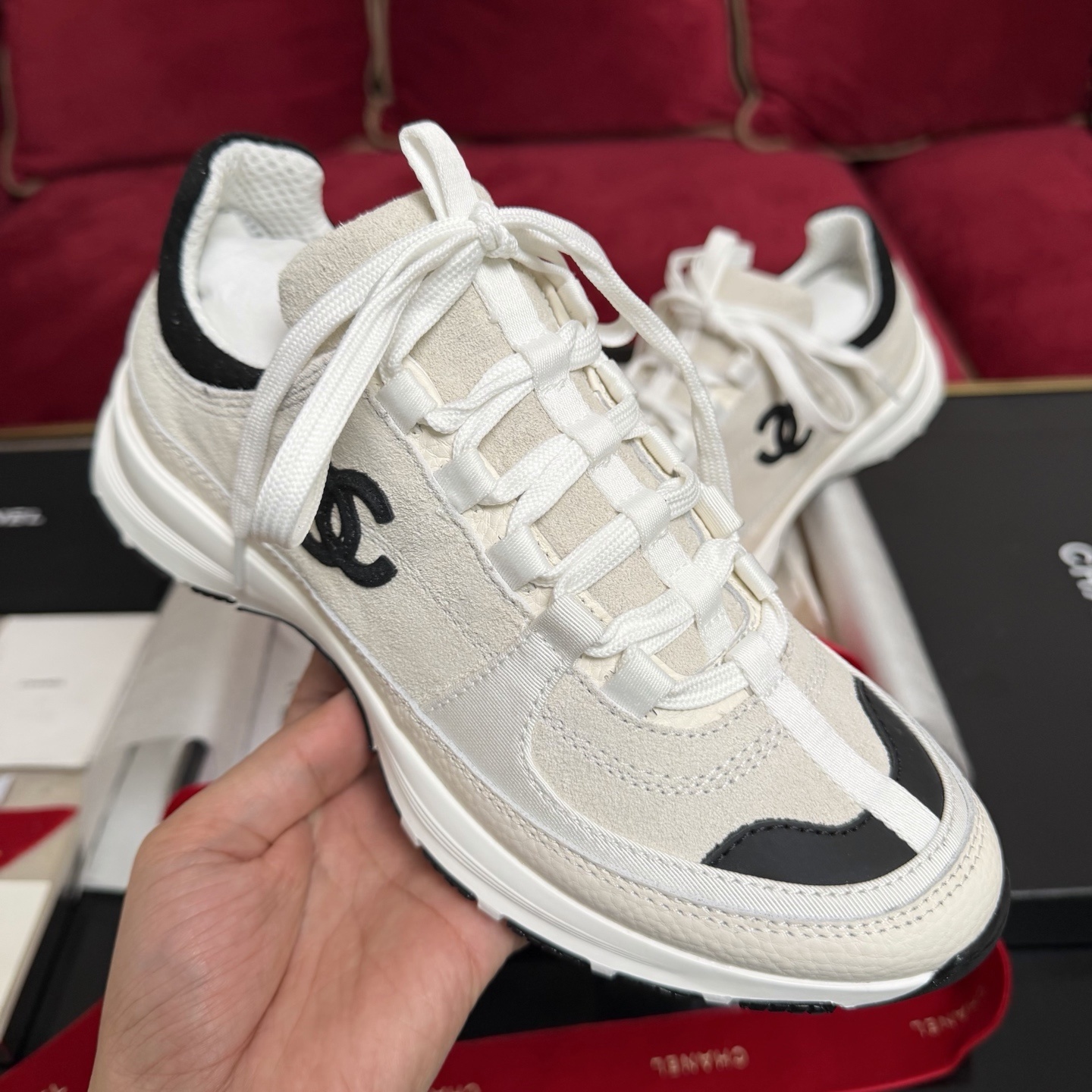 Authentic Chanel sneakers in cream and black featuring the iconic CC logo, presented in a luxury box with red ribbons. - Hình 4