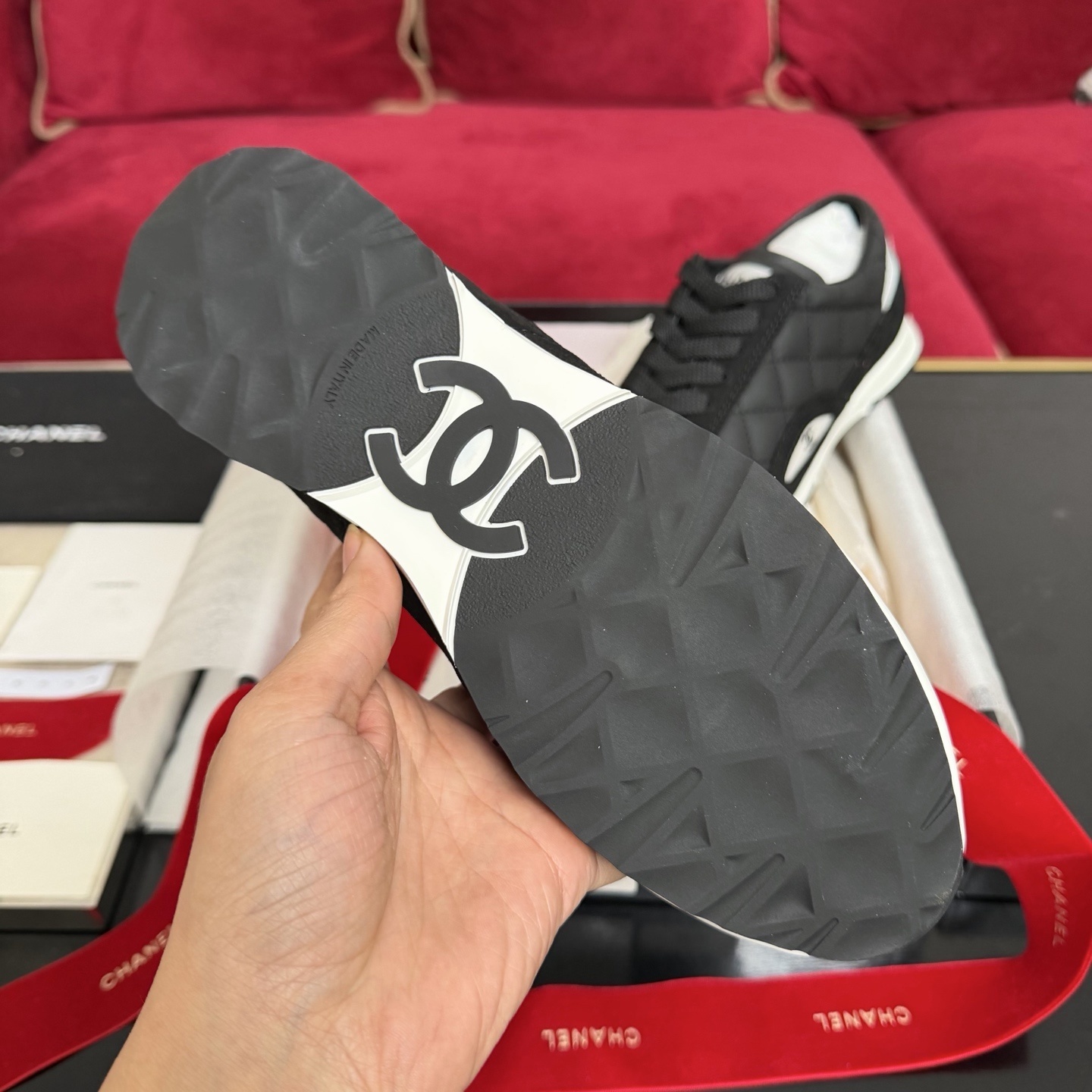 A pair of Chanel black quilted leather sneakers with white soles presented in luxury packaging with red ribbons - Hình 9