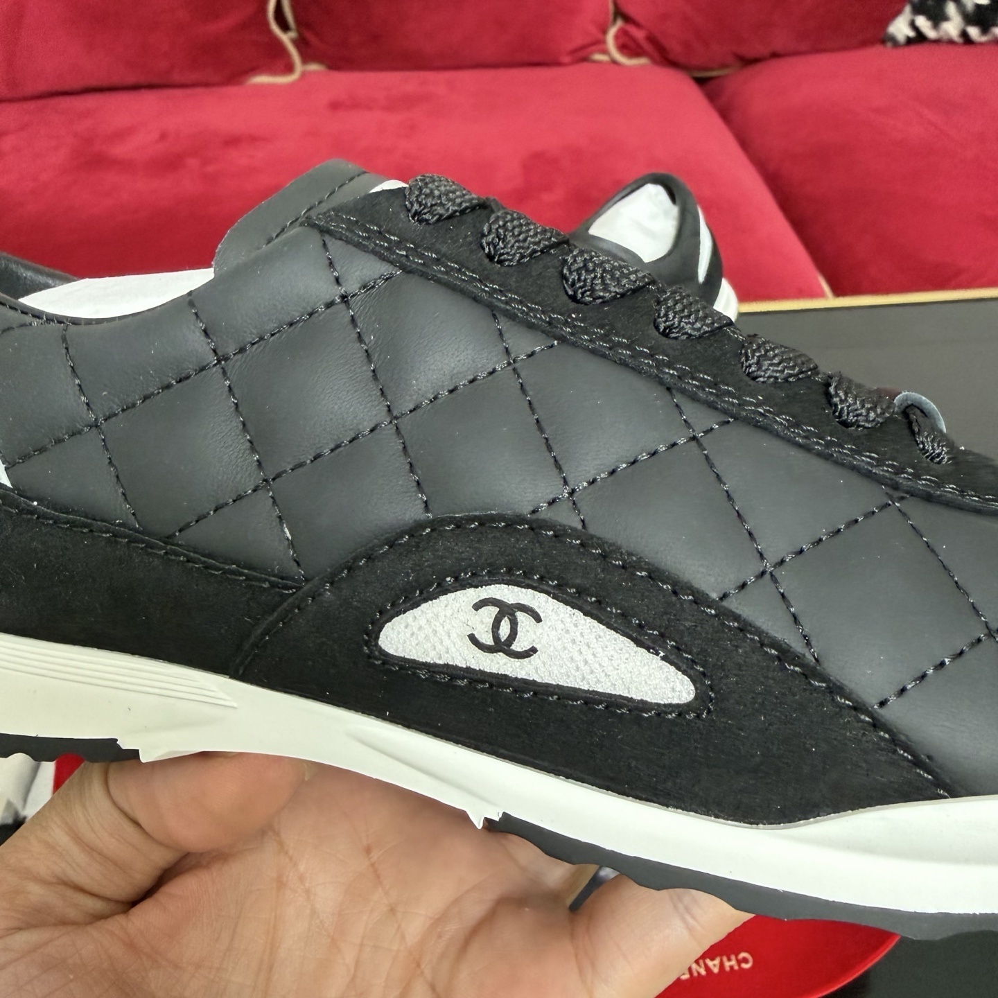 A pair of Chanel black quilted leather sneakers with white soles presented in luxury packaging with red ribbons - Hình 7