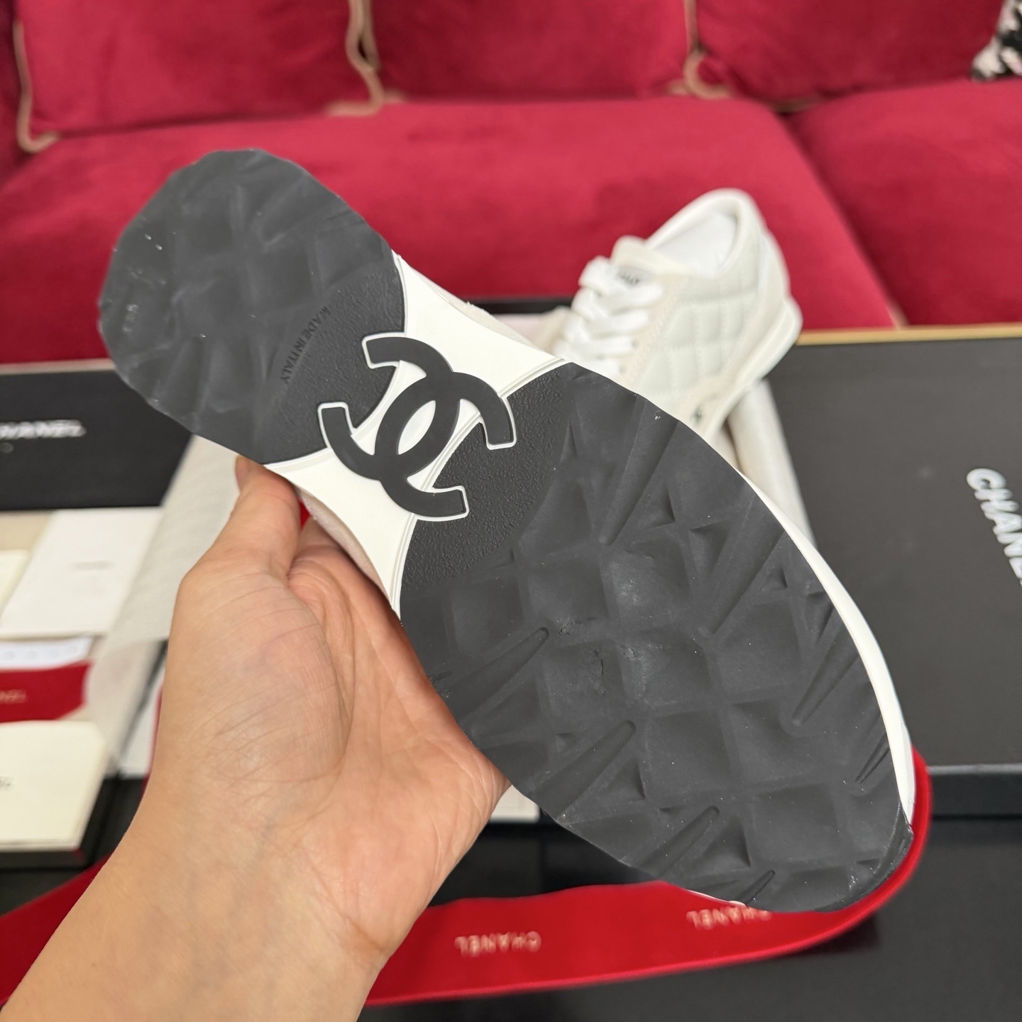 A pair of luxury white Chanel quilted leather sneakers displayed with original black box and decorative red ribbons. - Hình 9