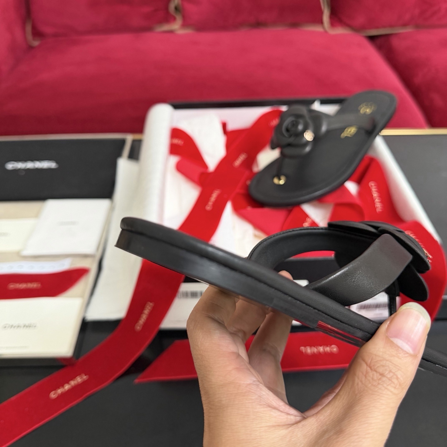 Black Chanel leather thong sandals with 3D Camellia flower and gold CC logo in a luxury gift box with red ribbons. - Hình 8