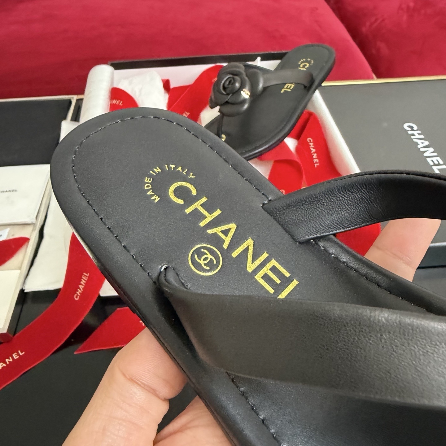 Black Chanel leather thong sandals with 3D Camellia flower and gold CC logo in a luxury gift box with red ribbons. - Hình 7