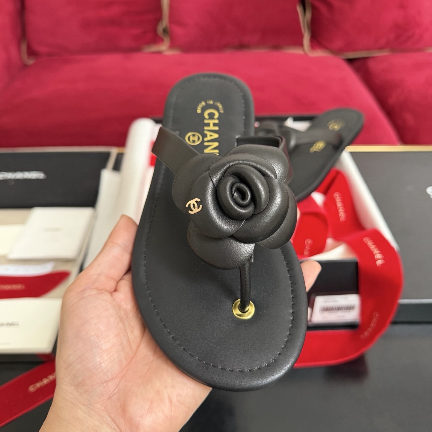 Black Chanel leather thong sandals with 3D Camellia flower and gold CC logo in a luxury gift box with red ribbons. - Hình 3