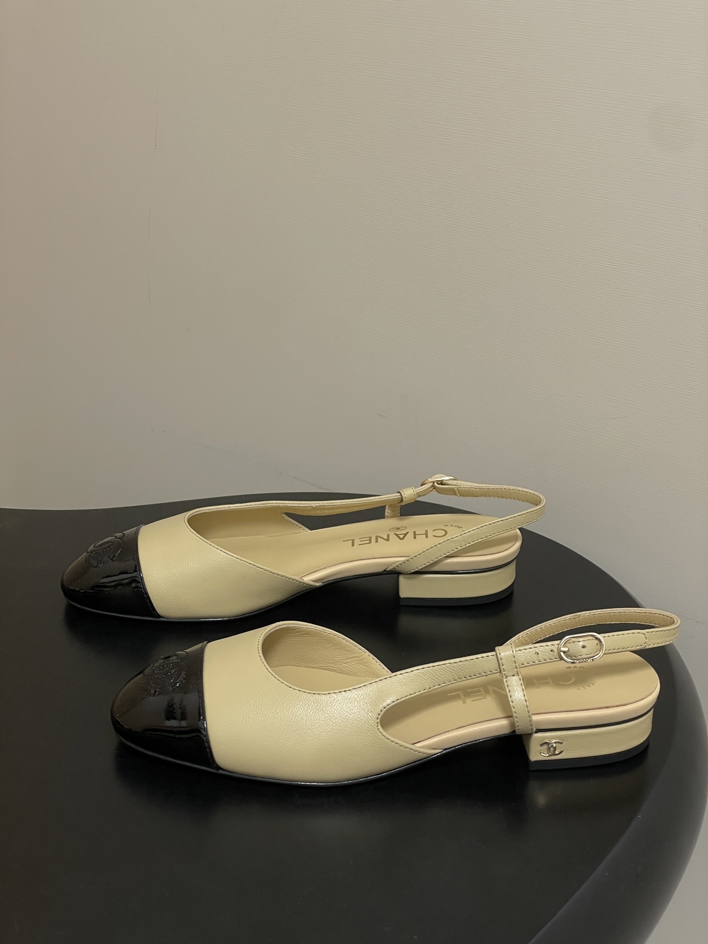 A pair of classic Chanel beige leather slingback pumps with black patent leather cap toes and low block heels. - Hình 3