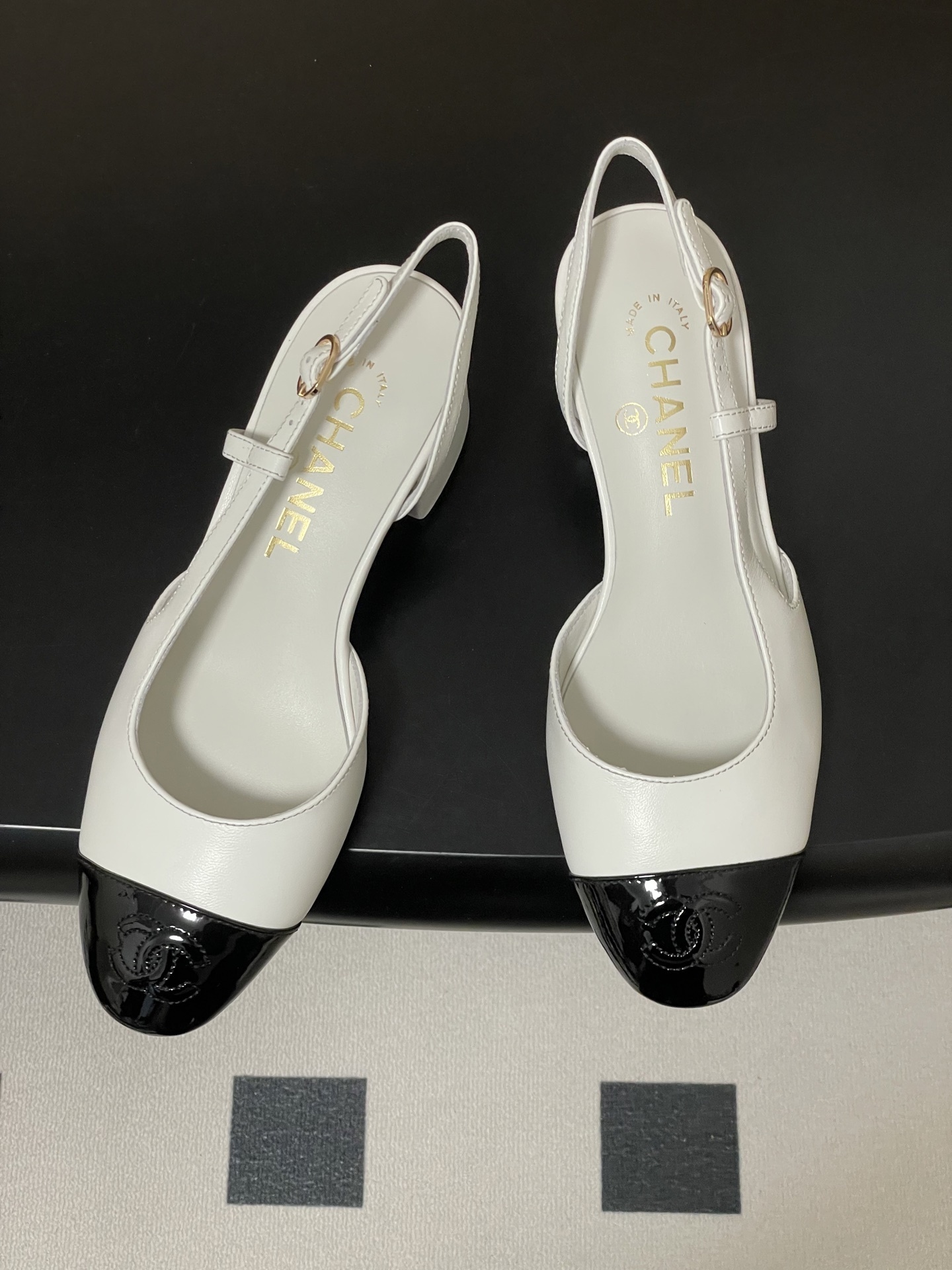 Luxury Chanel slingback pumps in white leather with black patent cap toe and block heel featuring gold CC logo. - Hình 2