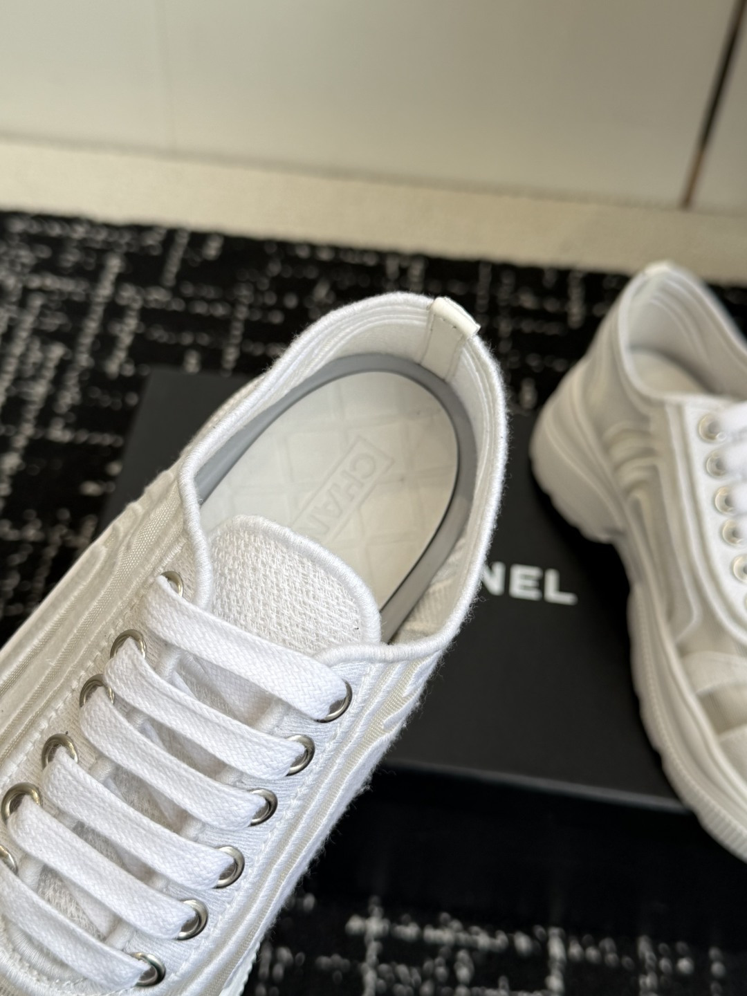 Pair of Chanel white mesh and fabric sneakers with CC logo on the toe cap and chunky sole, displayed on a black box. - Hình 7