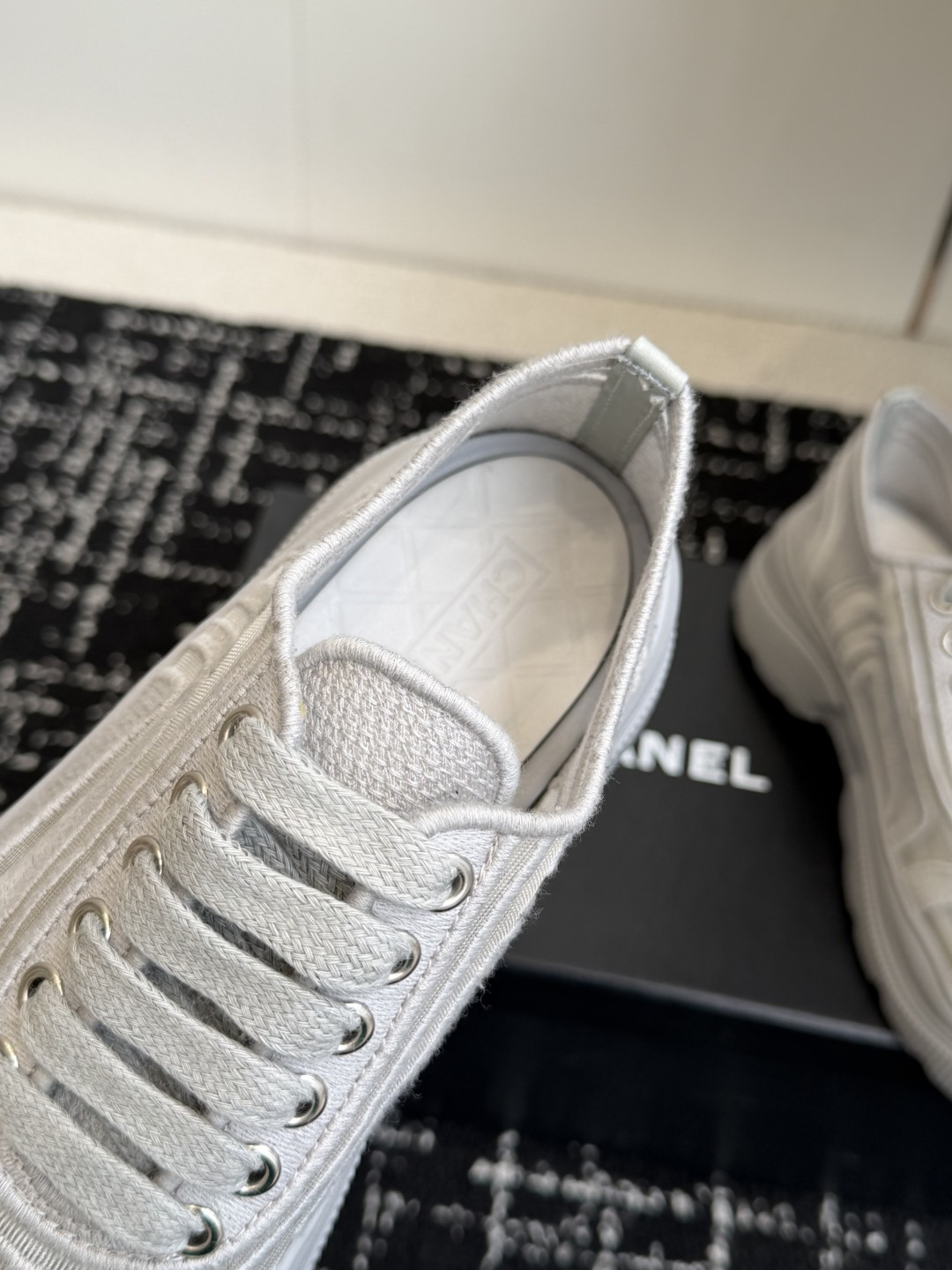 A pair of Chanel white mesh and fabric platform sneakers with the CC logo on the toe cap, displayed on a black box. - Hình 7