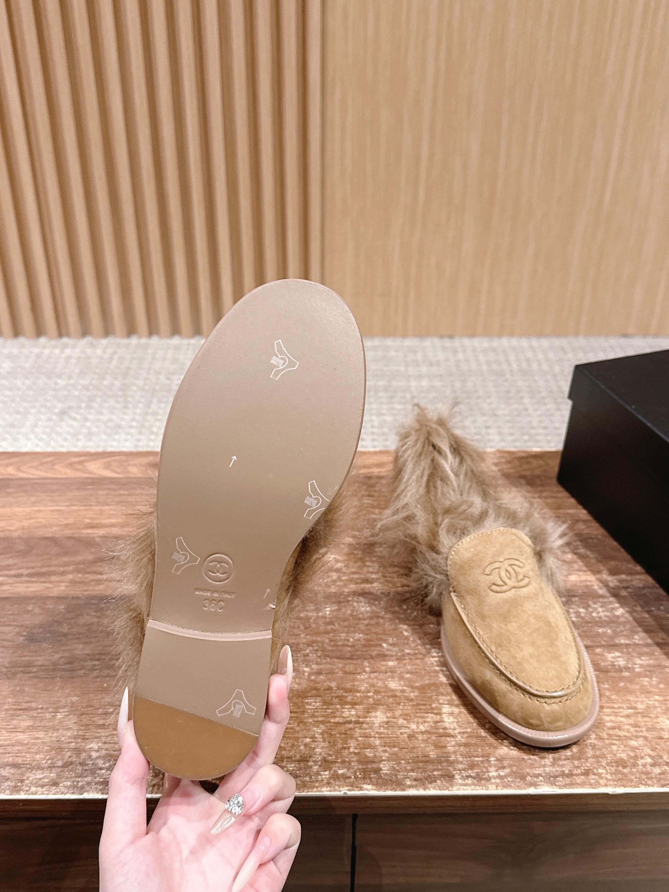 A pair of tan Chanel suede loafers with fluffy brown fur trim and embossed CC logo on a wooden surface next to a black shoe box. - Hình 9