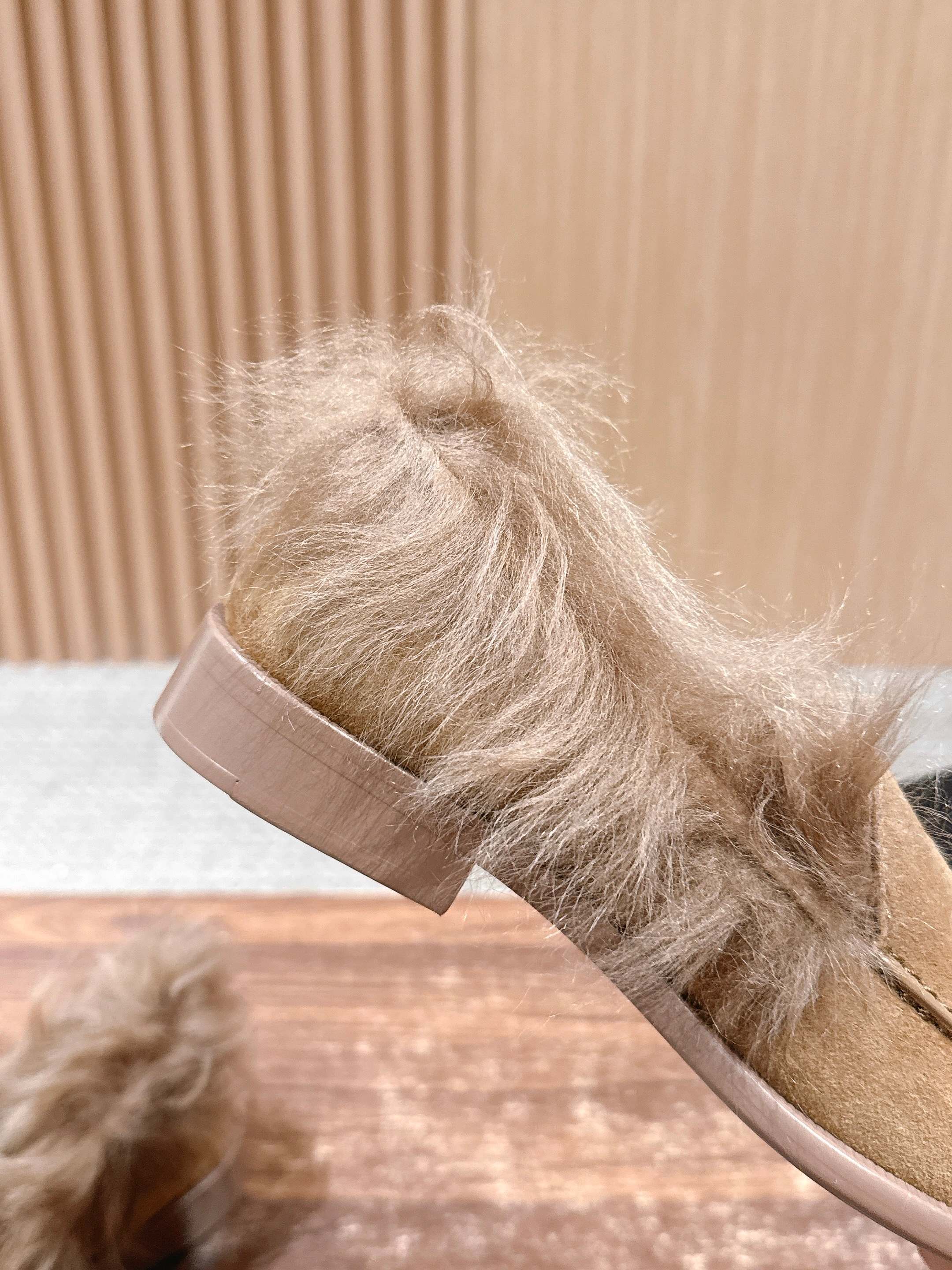 A pair of tan Chanel suede loafers with fluffy brown fur trim and embossed CC logo on a wooden surface next to a black shoe box. - Hình 7