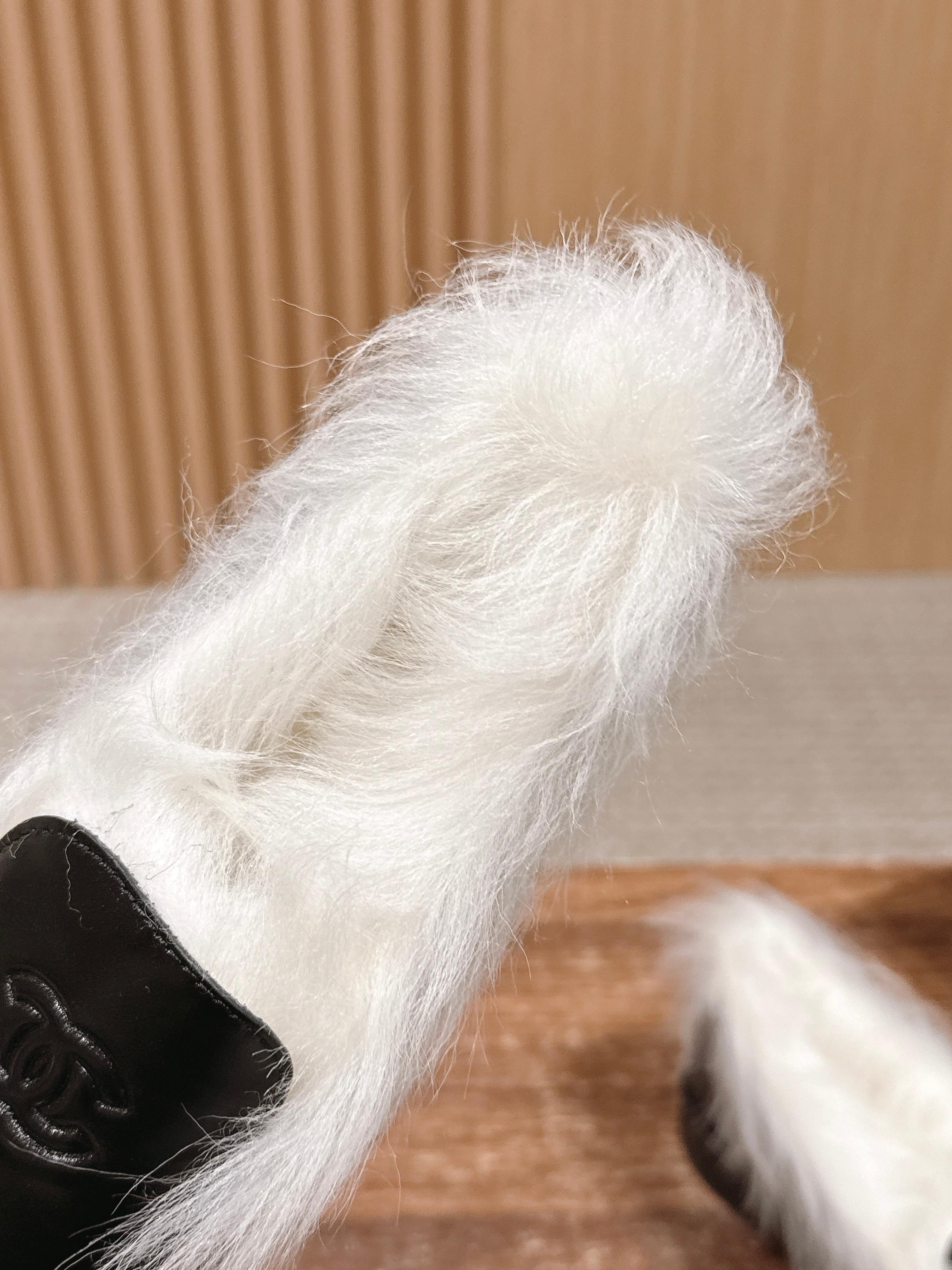 A pair of luxury black leather Chanel loafers with prominent white fur lining and CC logo on a wooden surface. - Hình 7