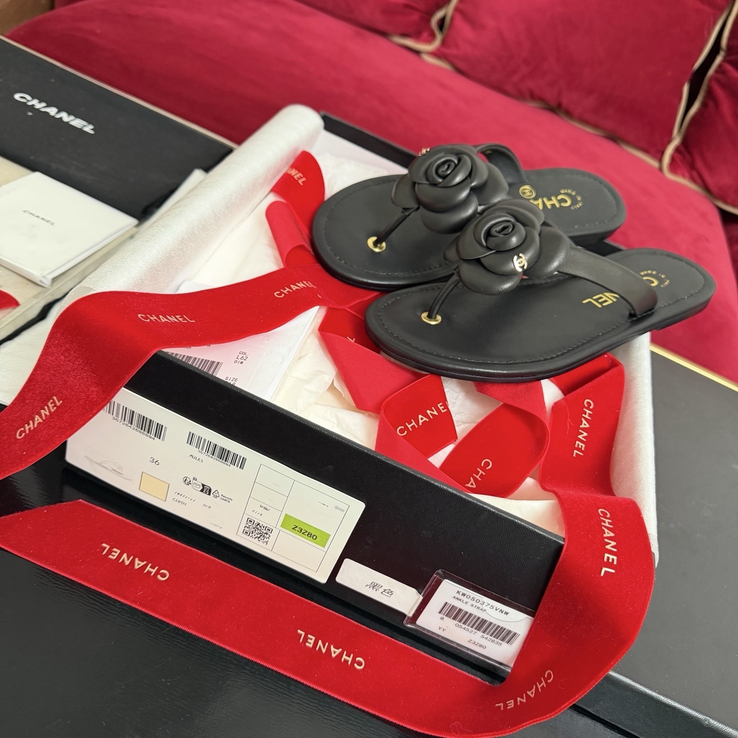 Black Chanel Camellia thong sandals with 3D flower detail and gold CC logo in original packaging with red ribbon. - Hình 2
