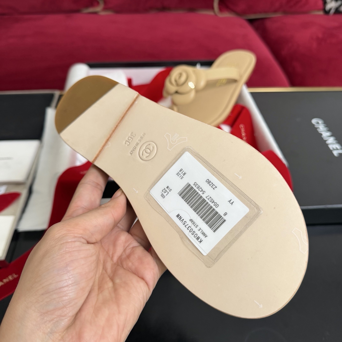 Pair of beige Chanel leather thong sandals featuring a large 3D camellia flower and gold CC logo detail, shown with original luxury packaging. - Hình 9