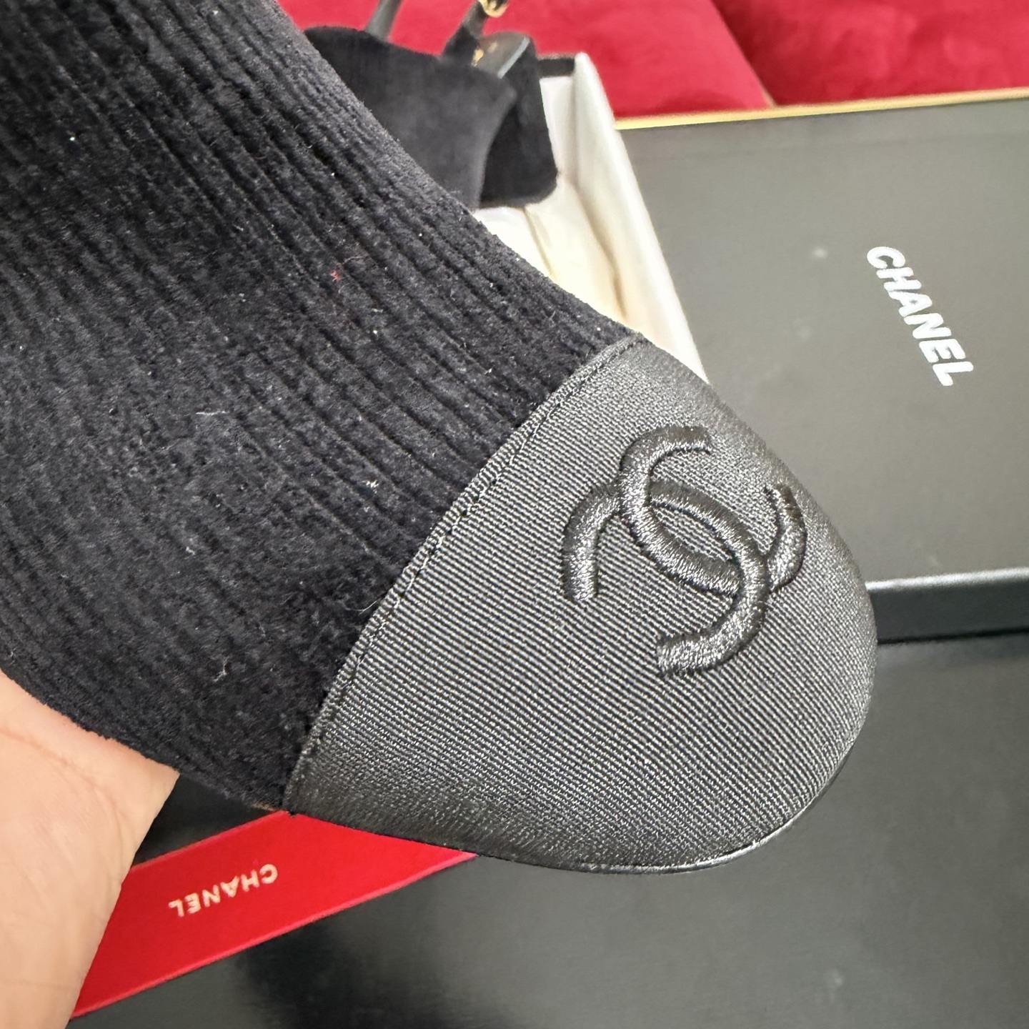 A pair of black Chanel ribbed fabric slingback pumps with a CC logo on the cap toe, displayed in their original box with a red ribbon. - Hình 6