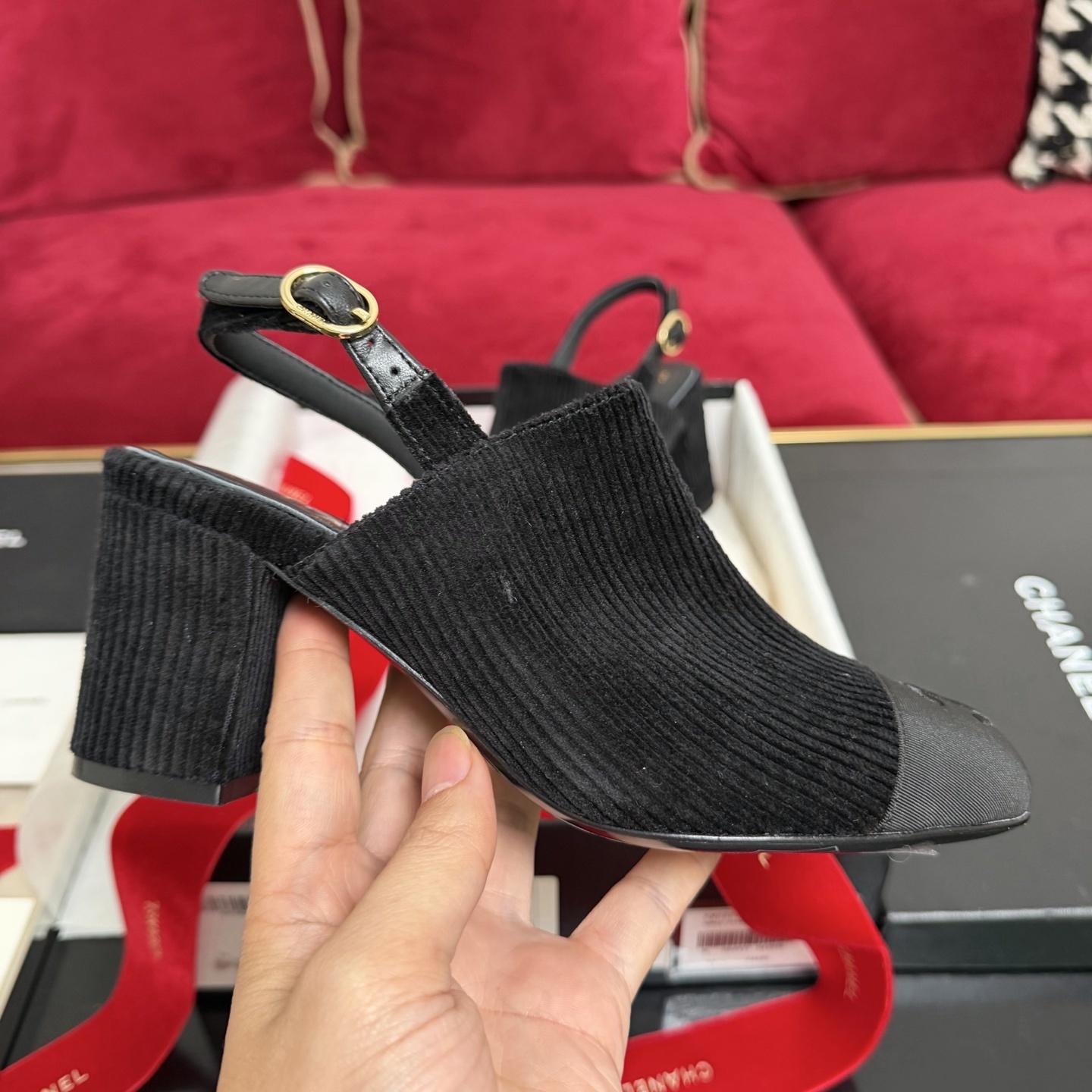 A pair of black Chanel ribbed fabric slingback pumps with a CC logo on the cap toe, displayed in their original box with a red ribbon. - Hình 5
