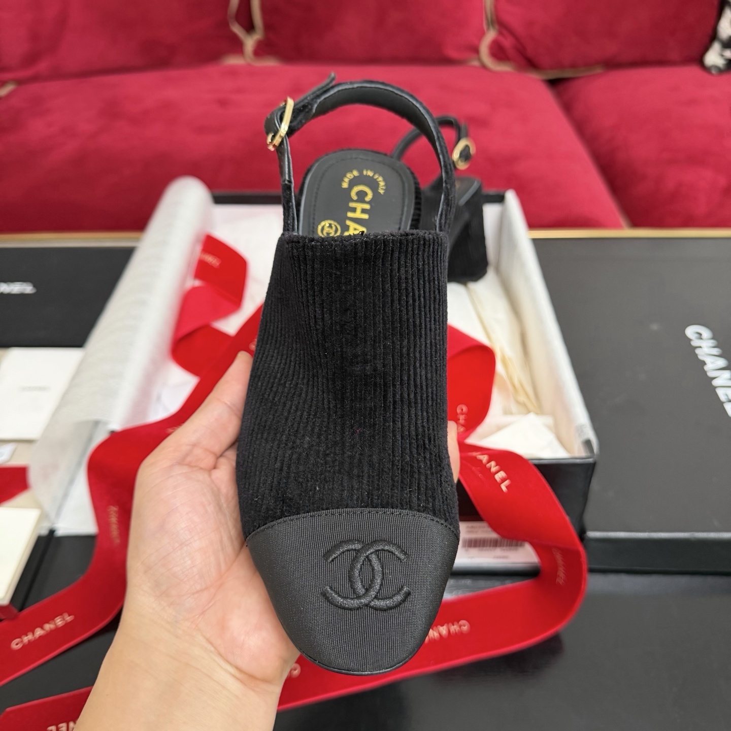 A pair of black Chanel ribbed fabric slingback pumps with a CC logo on the cap toe, displayed in their original box with a red ribbon. - Hình 3