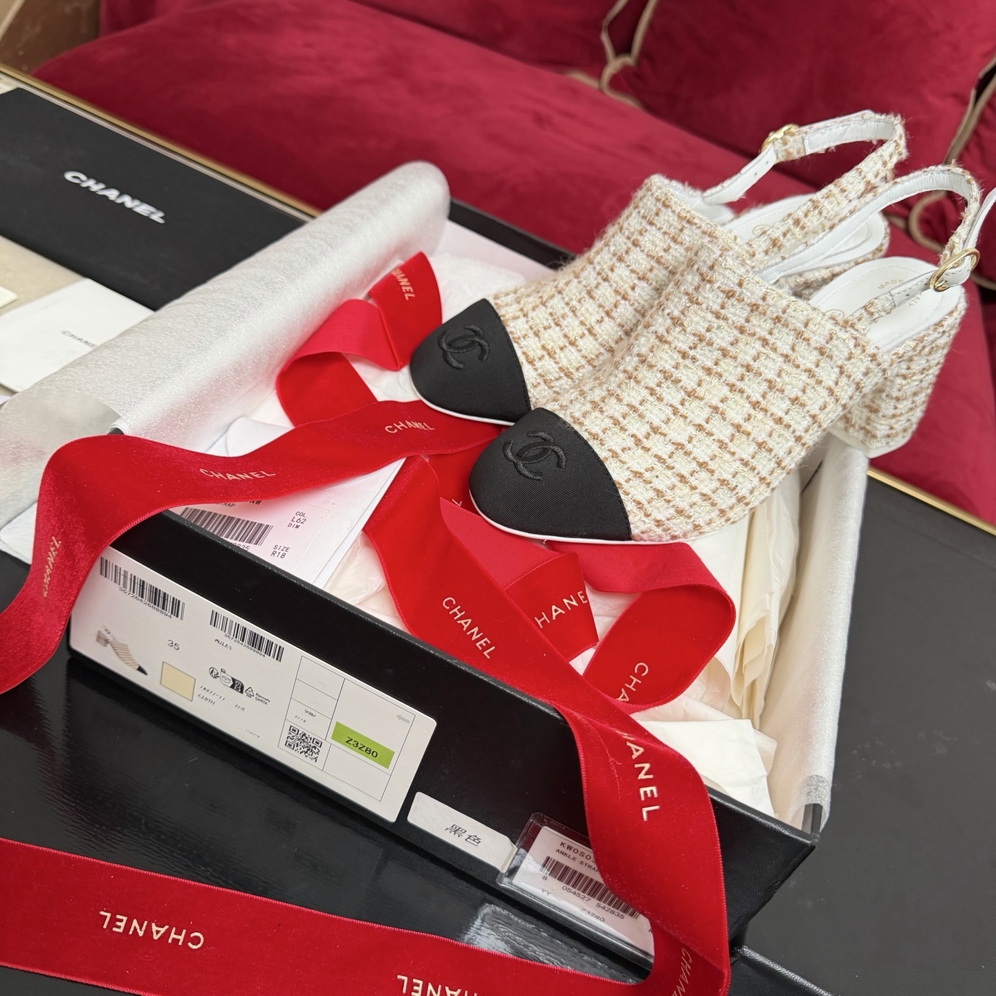 Luxury Chanel tweed slingback pumps with black cap toe and CC logo shown in original packaging with red ribbons. - Hình 2