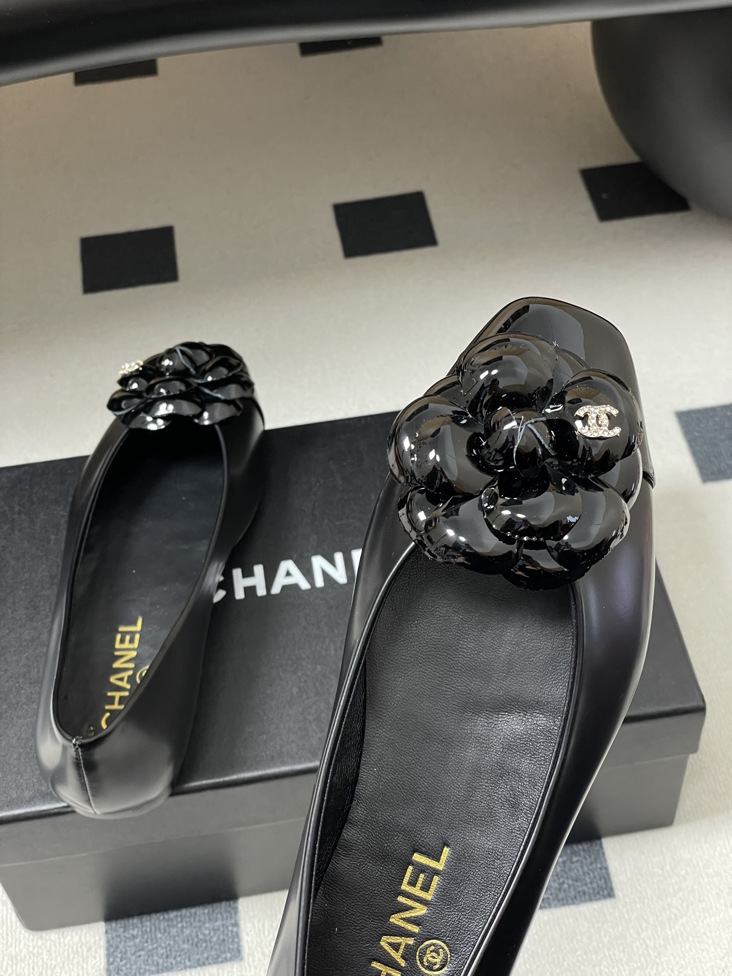 A pair of black Chanel ballet flats featuring a patent leather camellia flower with a small CC logo on the toe cap. - Hình 9