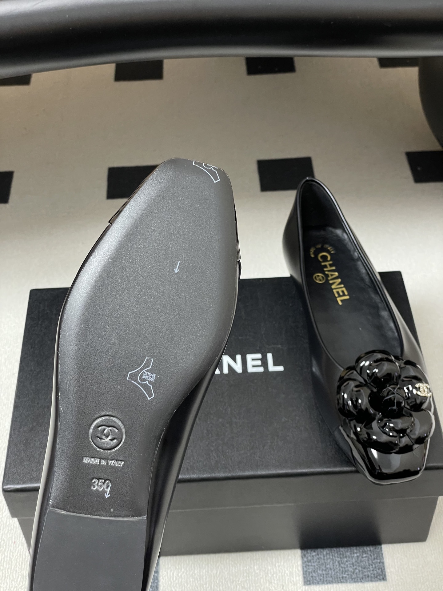 A pair of black Chanel ballet flats featuring a patent leather camellia flower with a small CC logo on the toe cap. - Hình 8