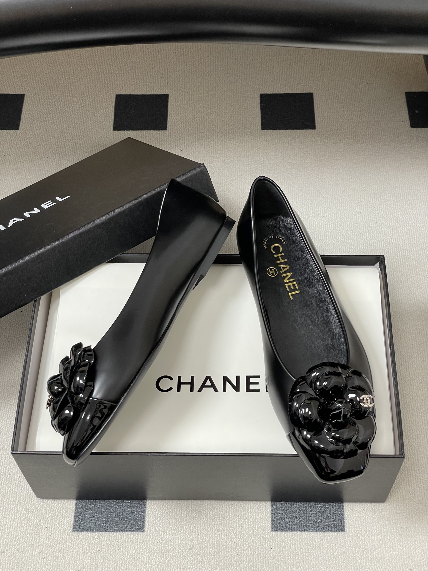 A pair of black Chanel ballet flats featuring a patent leather camellia flower with a small CC logo on the toe cap. - Hình 6