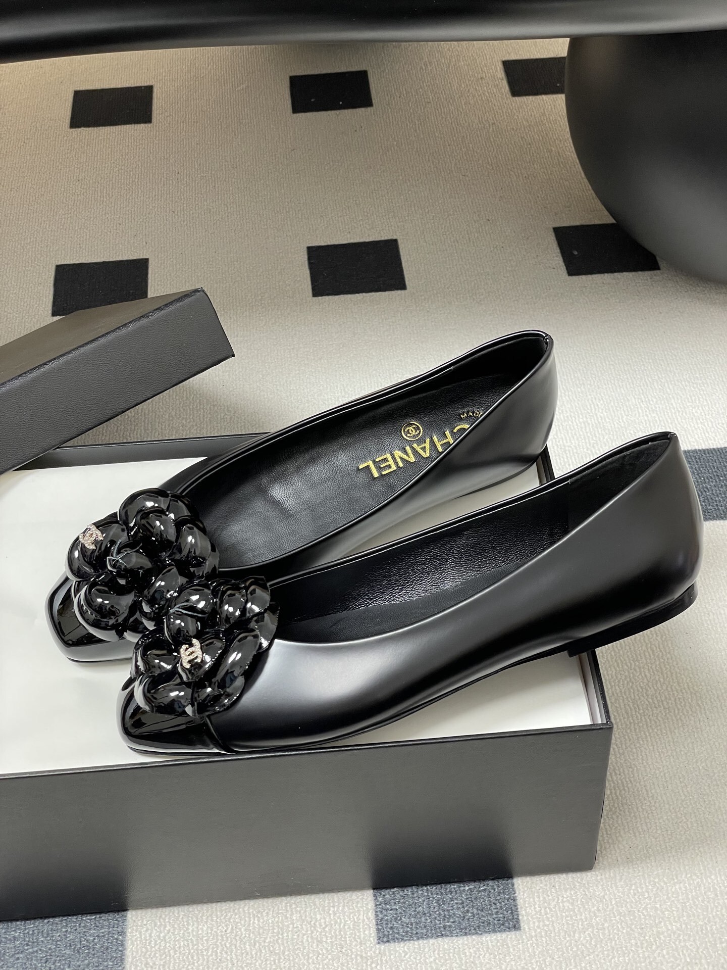 A pair of black Chanel ballet flats featuring a patent leather camellia flower with a small CC logo on the toe cap. - Hình 4