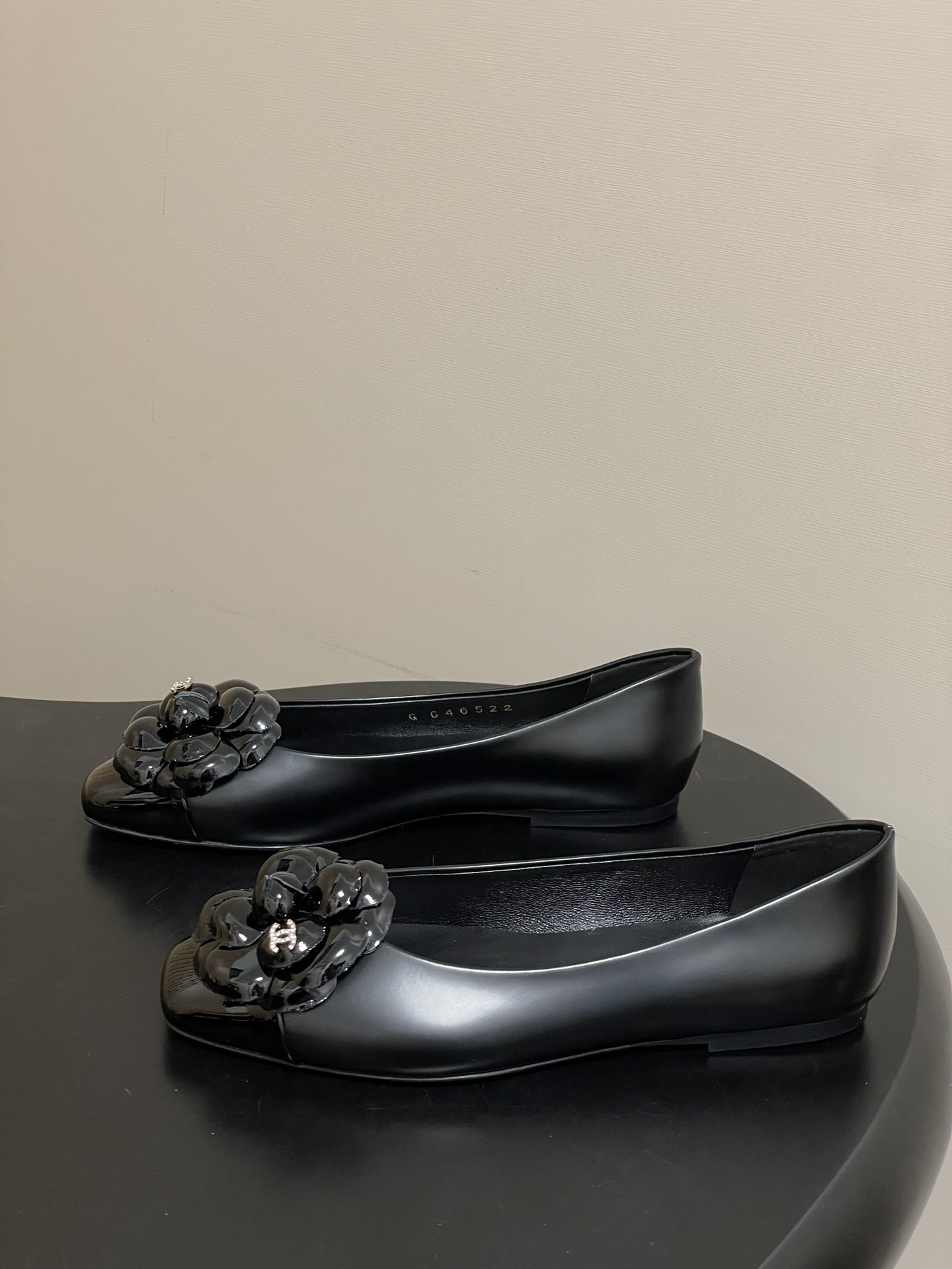 A pair of black Chanel ballet flats featuring a patent leather camellia flower with a small CC logo on the toe cap. - Hình 3