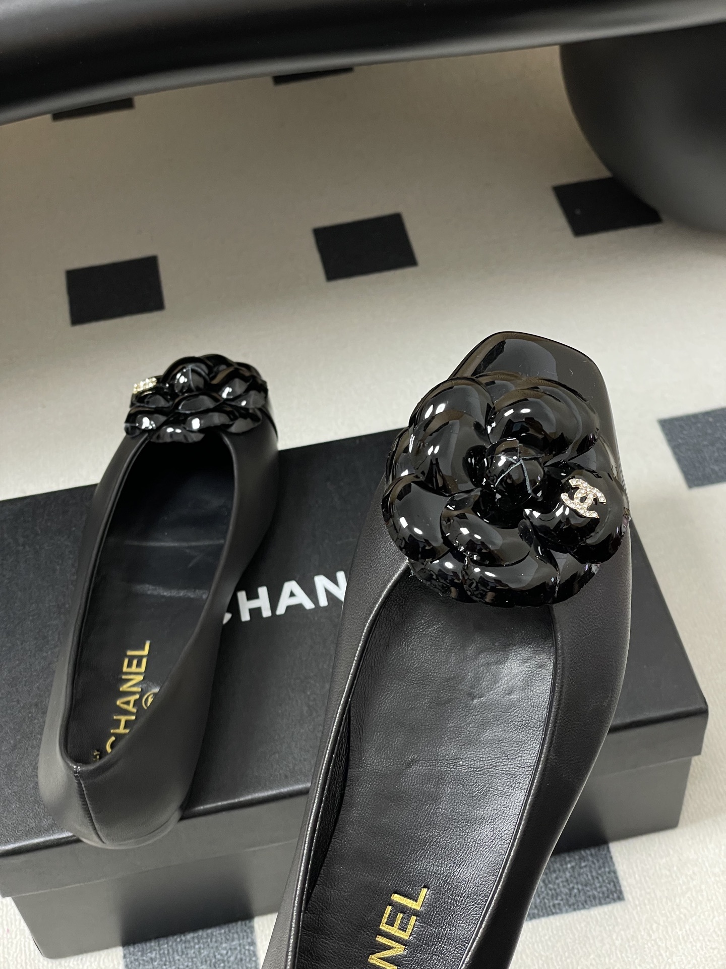A pair of black Chanel ballet flats featuring a 3D camellia flower and patent leather square toe. - Hình 9