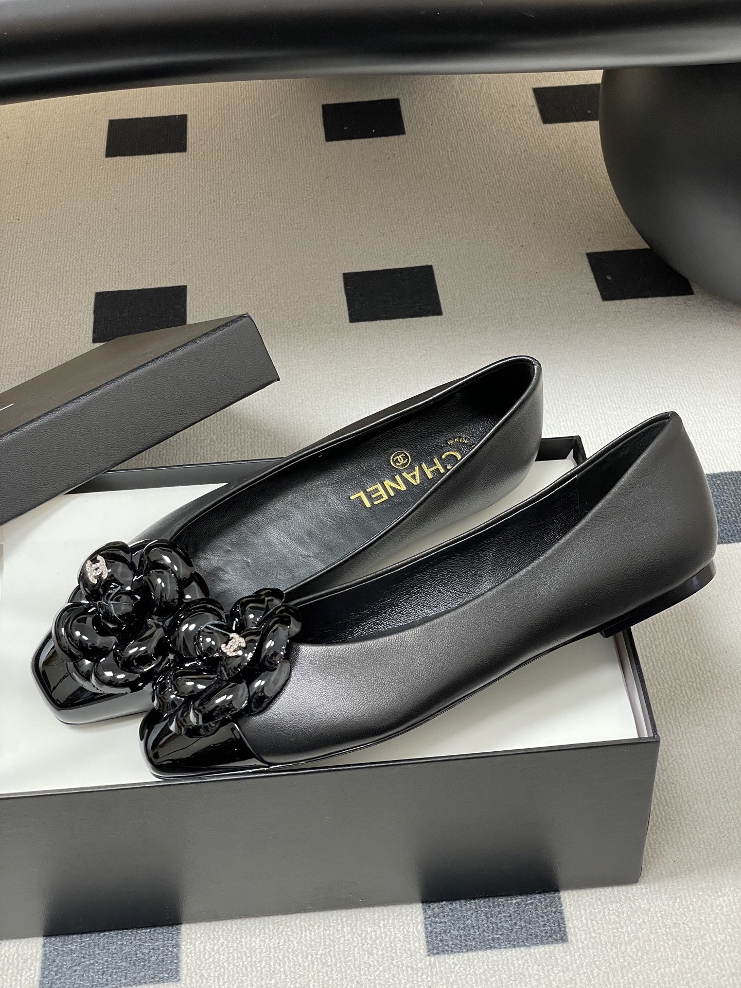 A pair of black Chanel ballet flats featuring a 3D camellia flower and patent leather square toe. - Hình 4