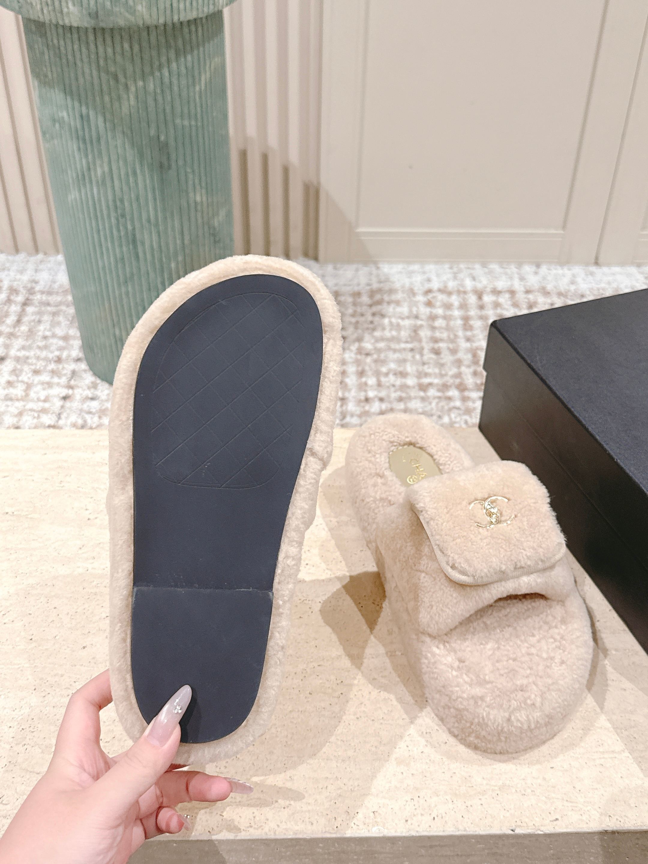 A pair of luxury beige Chanel shearling platform mules featuring gold CC logos on a stone pedestal. - Hình 9