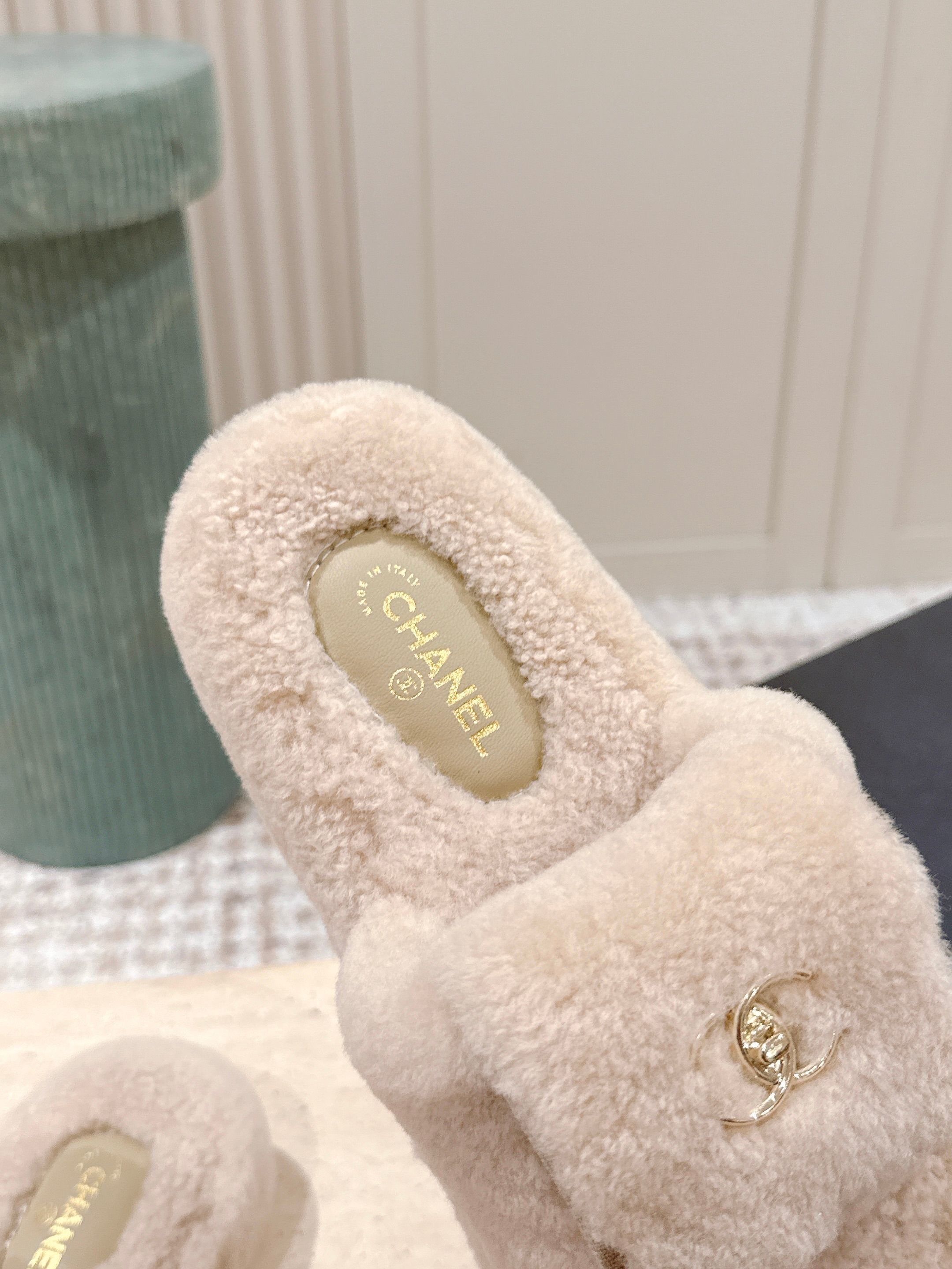 A pair of luxury beige Chanel shearling platform mules featuring gold CC logos on a stone pedestal. - Hình 7