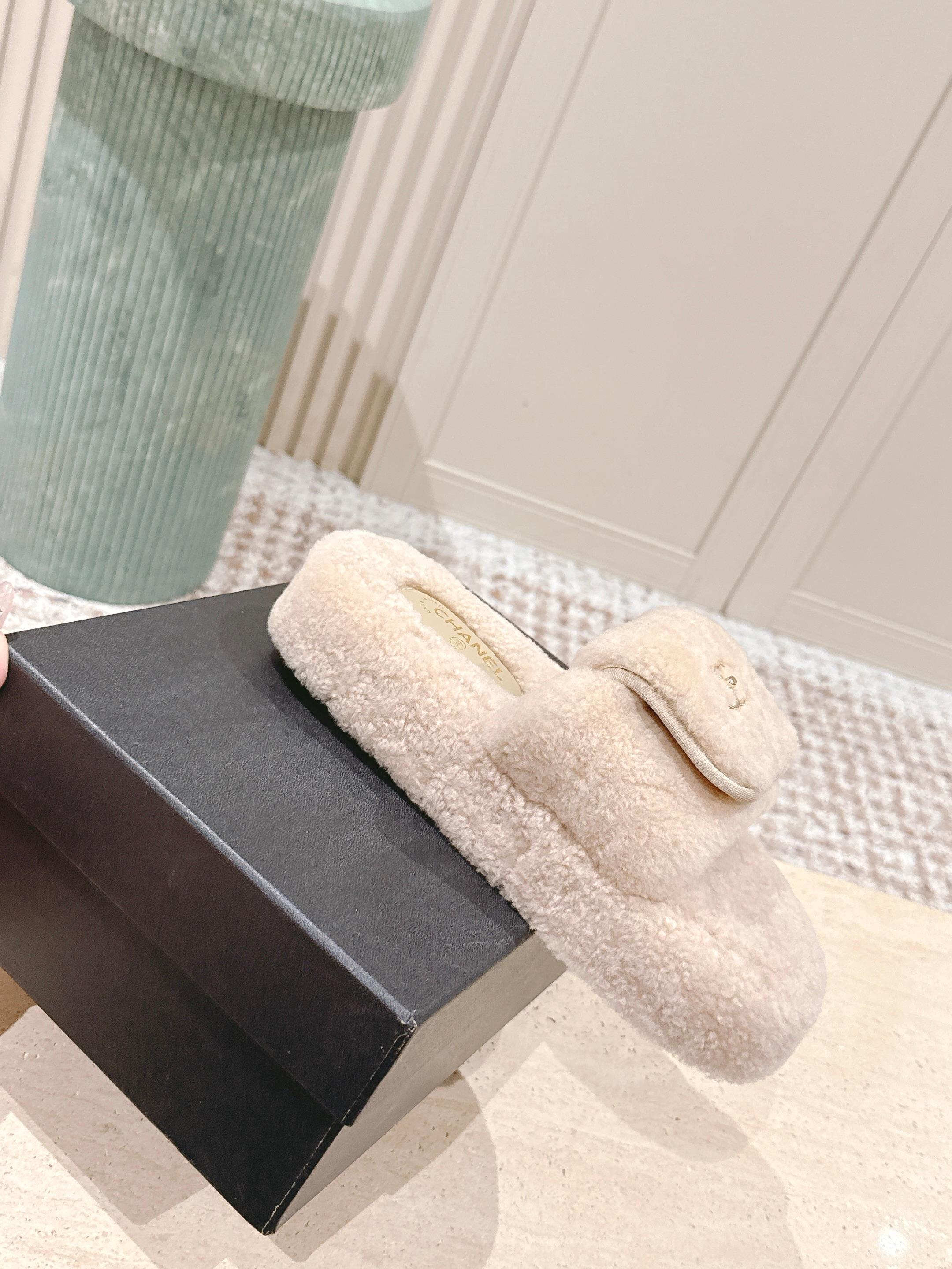 A pair of luxury beige Chanel shearling platform mules featuring gold CC logos on a stone pedestal. - Hình 4